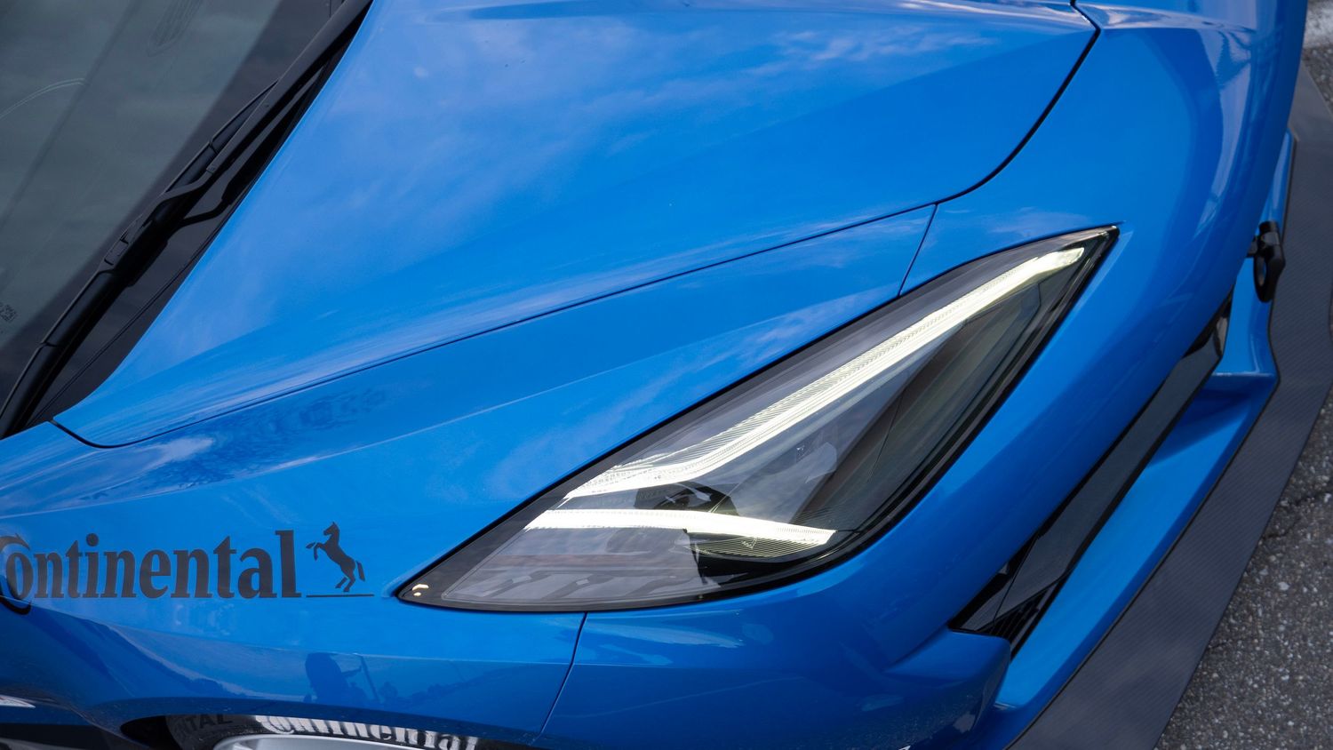 Extreme close-up of modern blue sports car headlight with sharp angular design.