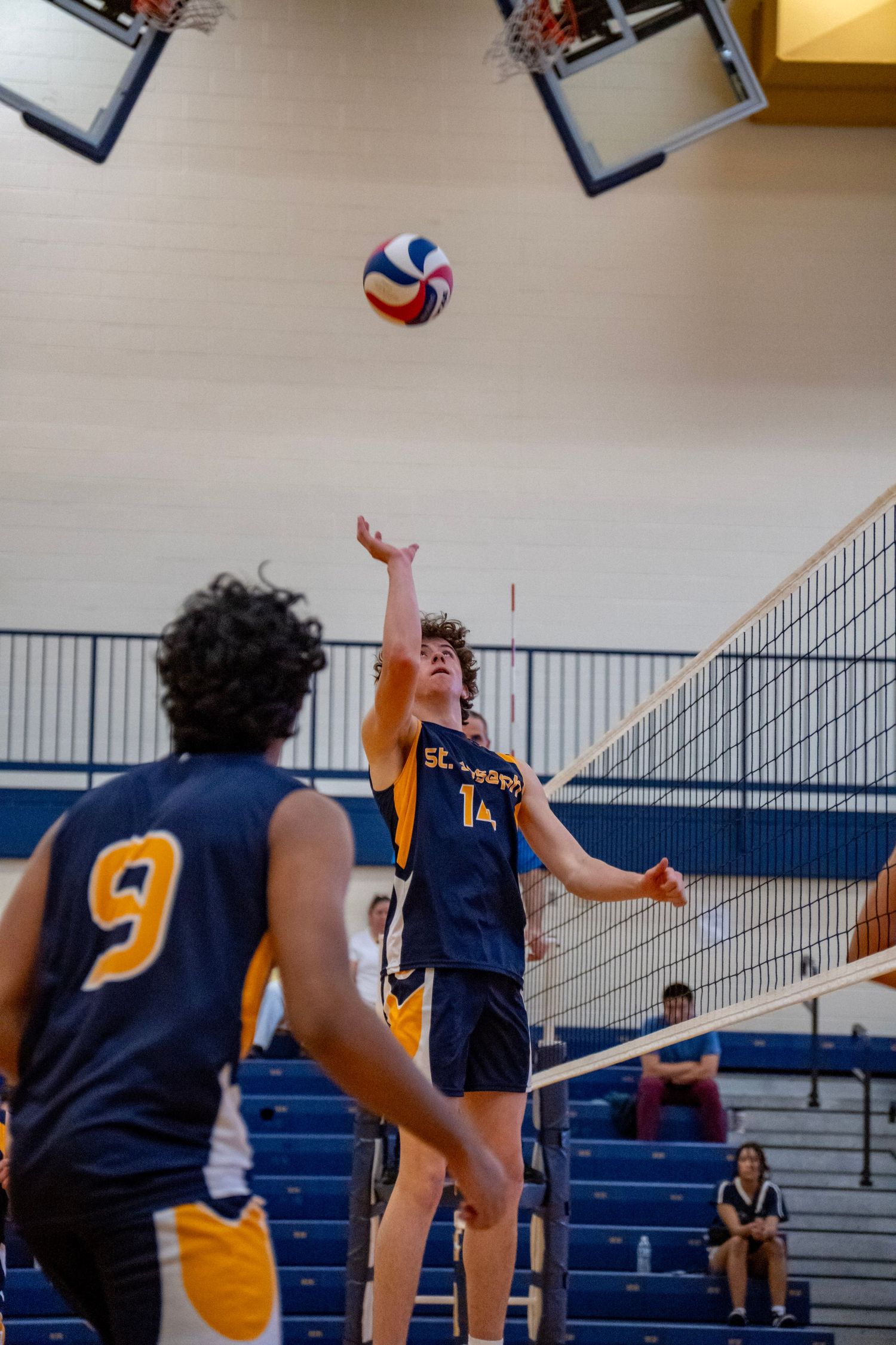 Players mid-game at a volleyball match with one player preparing to hit the ball.