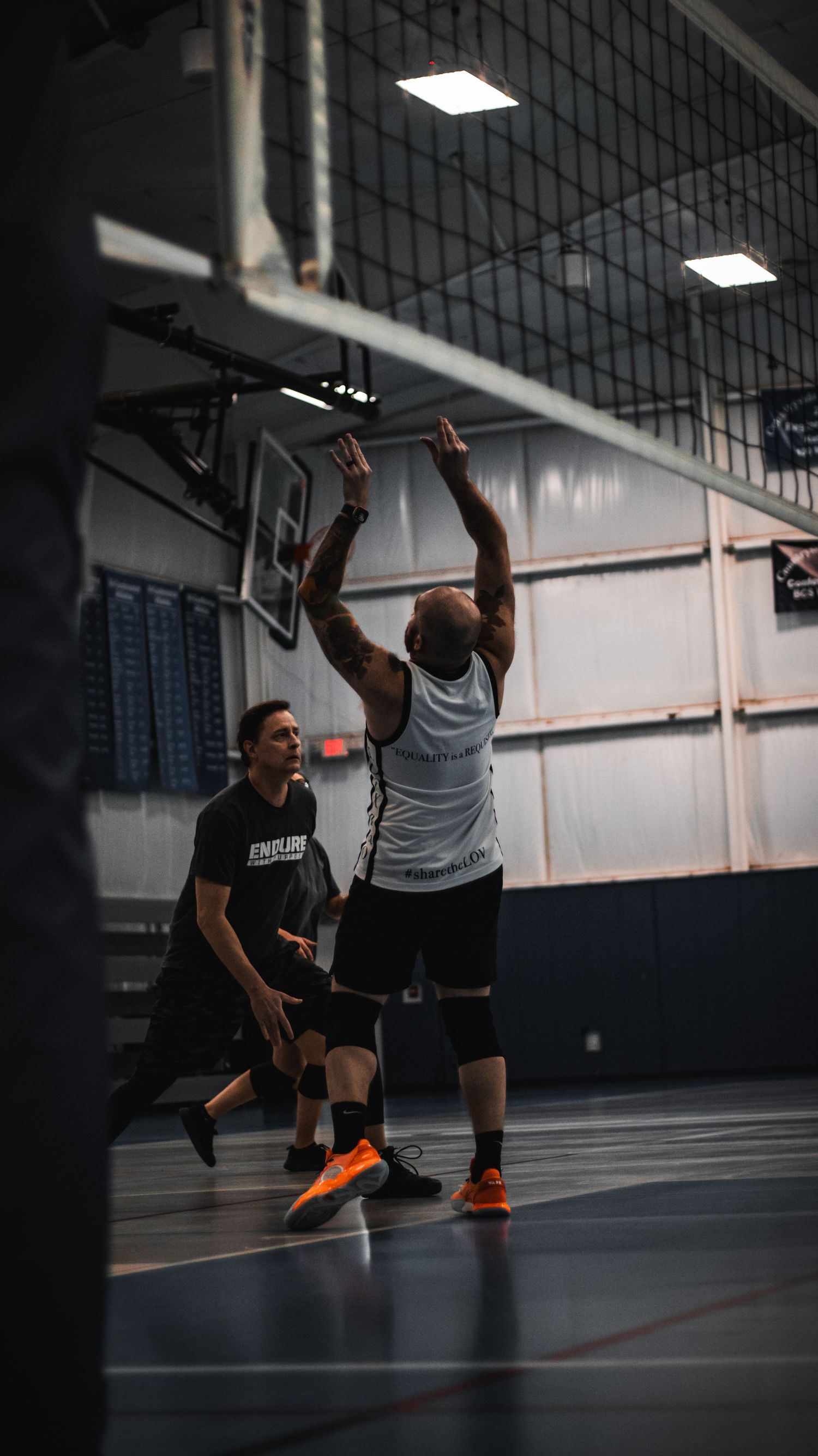 Players compete at the net during an intense indoor volleyball match.