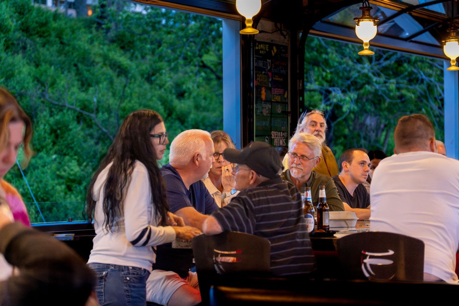 People dining outdoors at a casual restaurant patio with hanging pendant lights during evening hours.