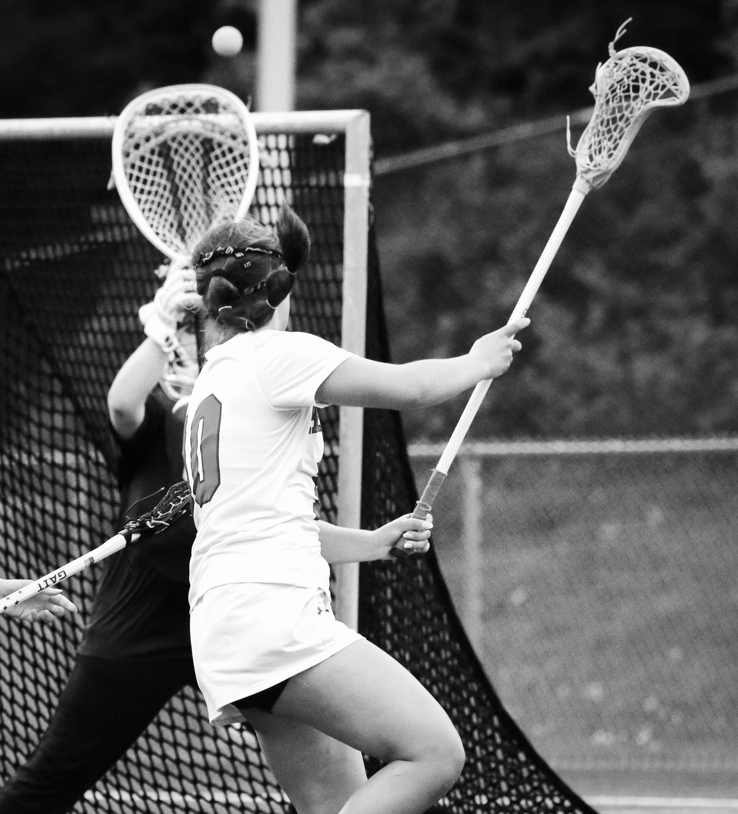 Athletic players dive for the ball during an intense lacrosse game match on the field.