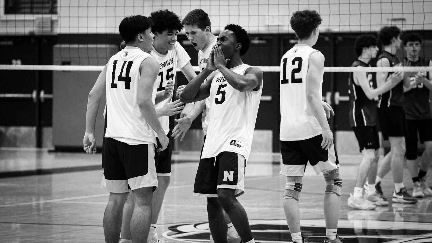 High school volleyball teammates huddle together during a timeout in a black and white photo.