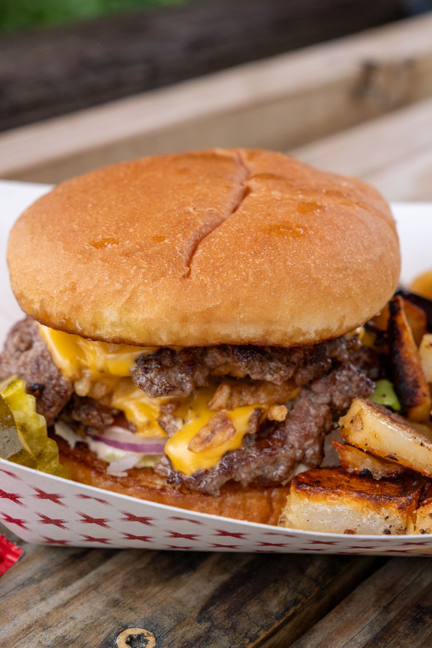 A juicy burger dripping with cheese and sauce is shown with fries