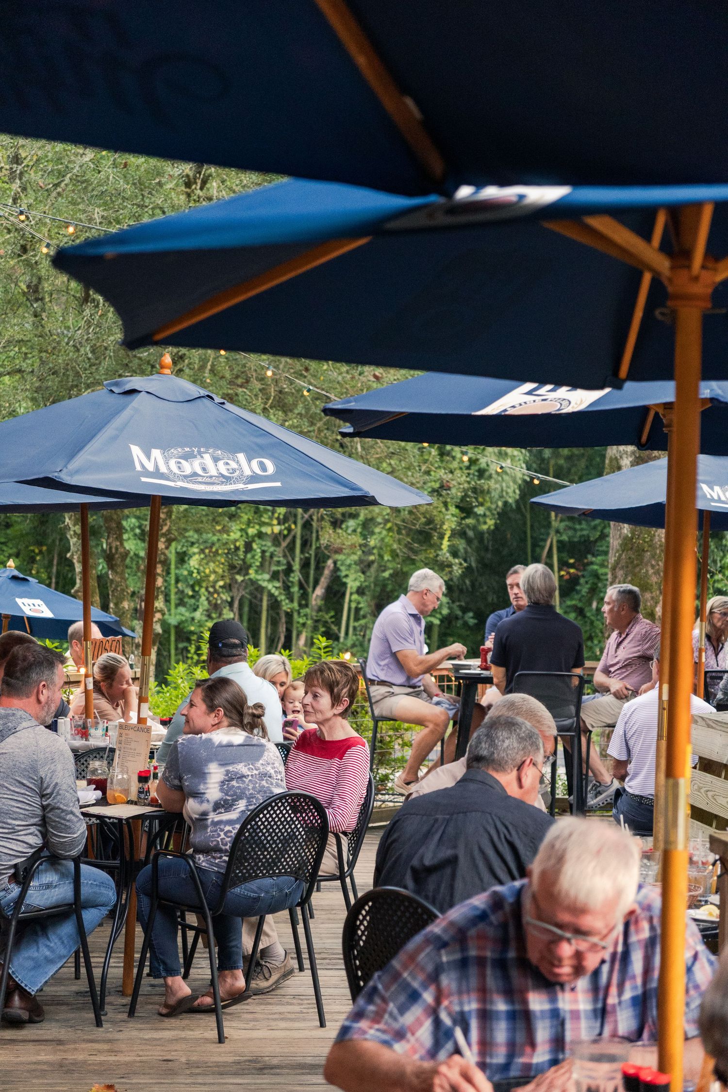 People happily eat and sit around tables at a local restaurant serving delicious food outdoors