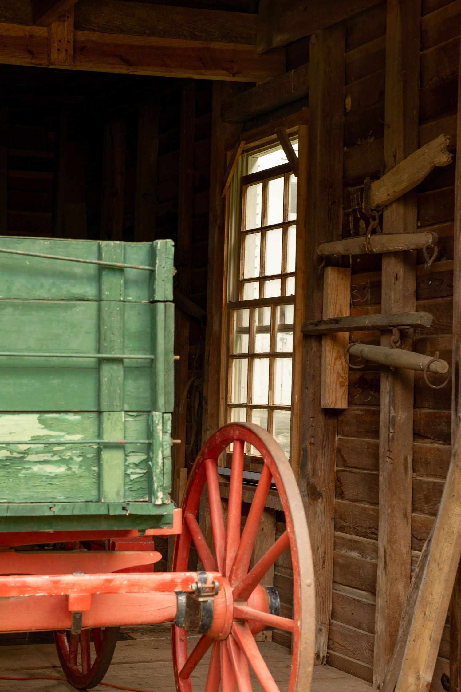 A green and red wagon is partially shown in a barn with a window behind.