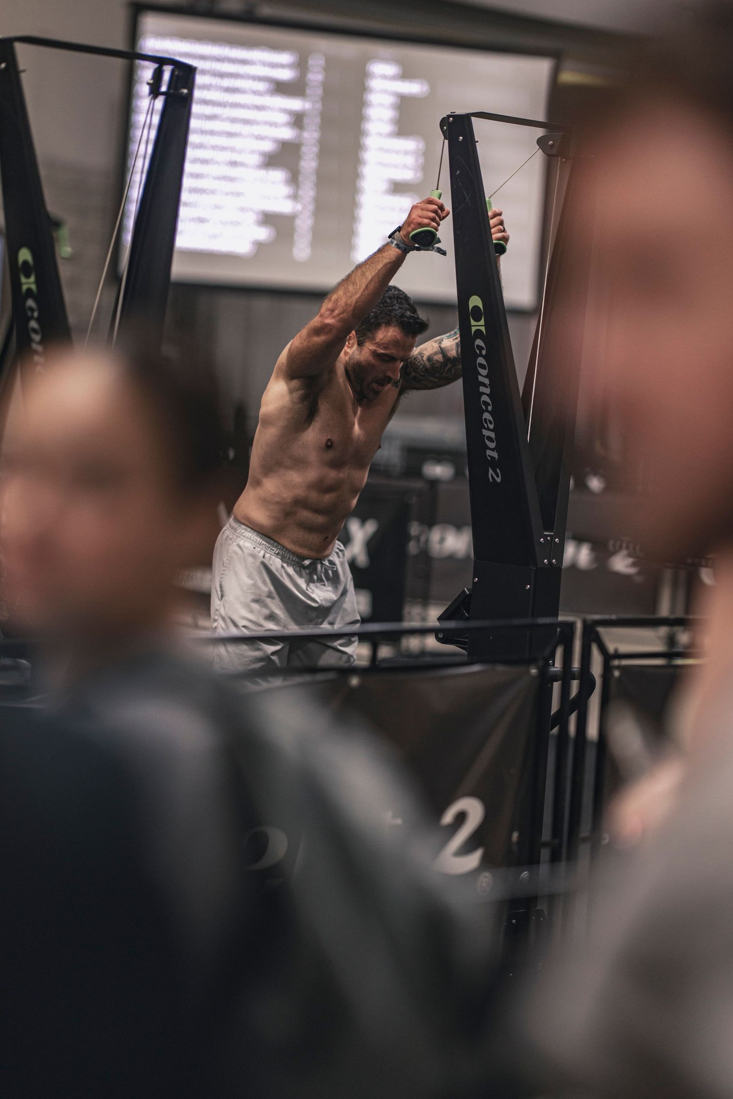 Athletic person using exercise equipment in a dimly lit gym environment.