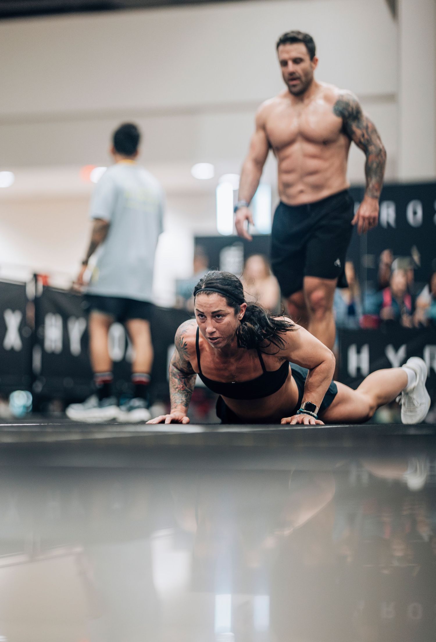 Athletes performing pushups and exercises on a gym floor during training.