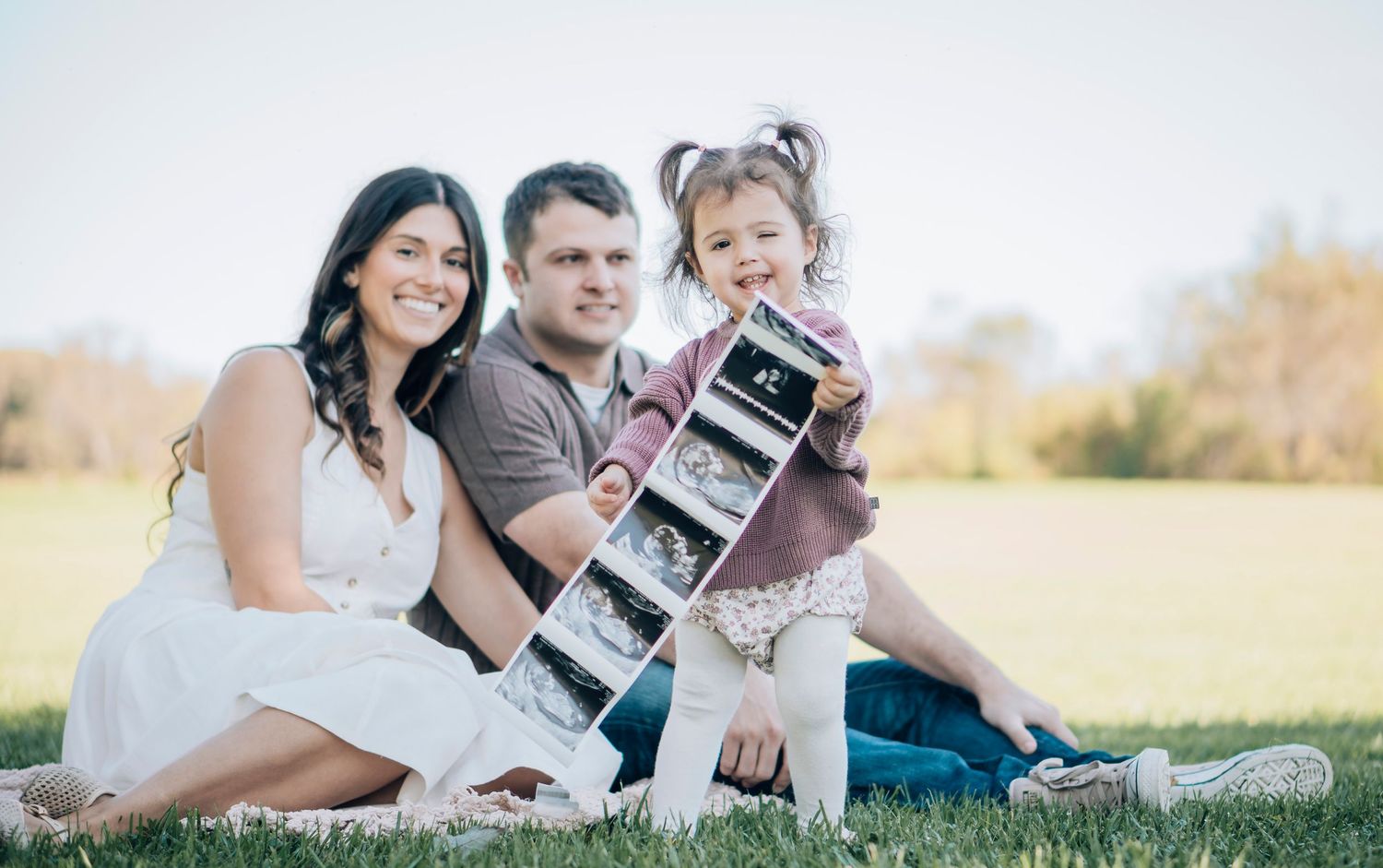 A collection of five outdoor family photographs arranged in a horizontal strip showing people relaxing on grass.