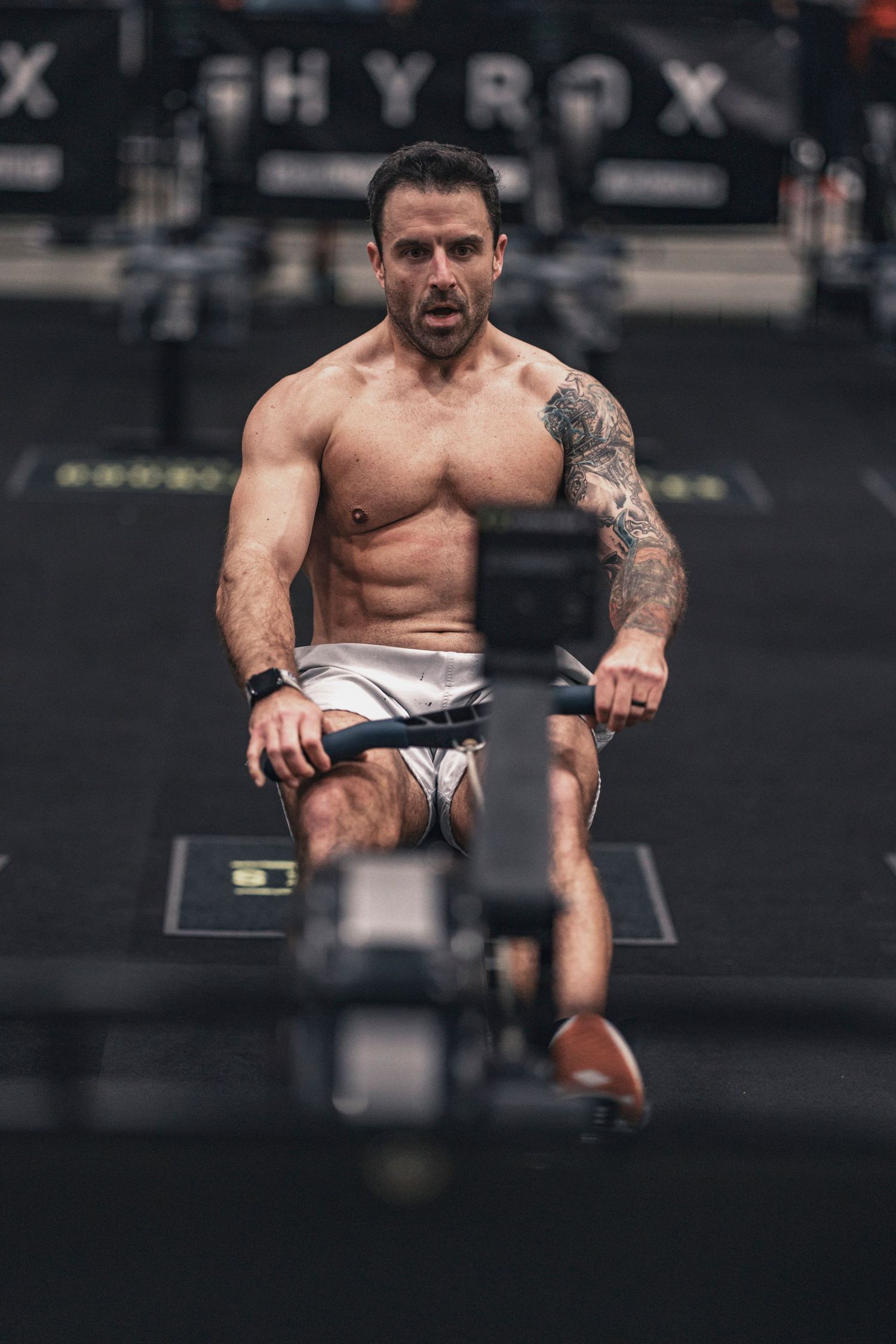 Athlete demonstrating proper form during rowing machine workout in gym setting.