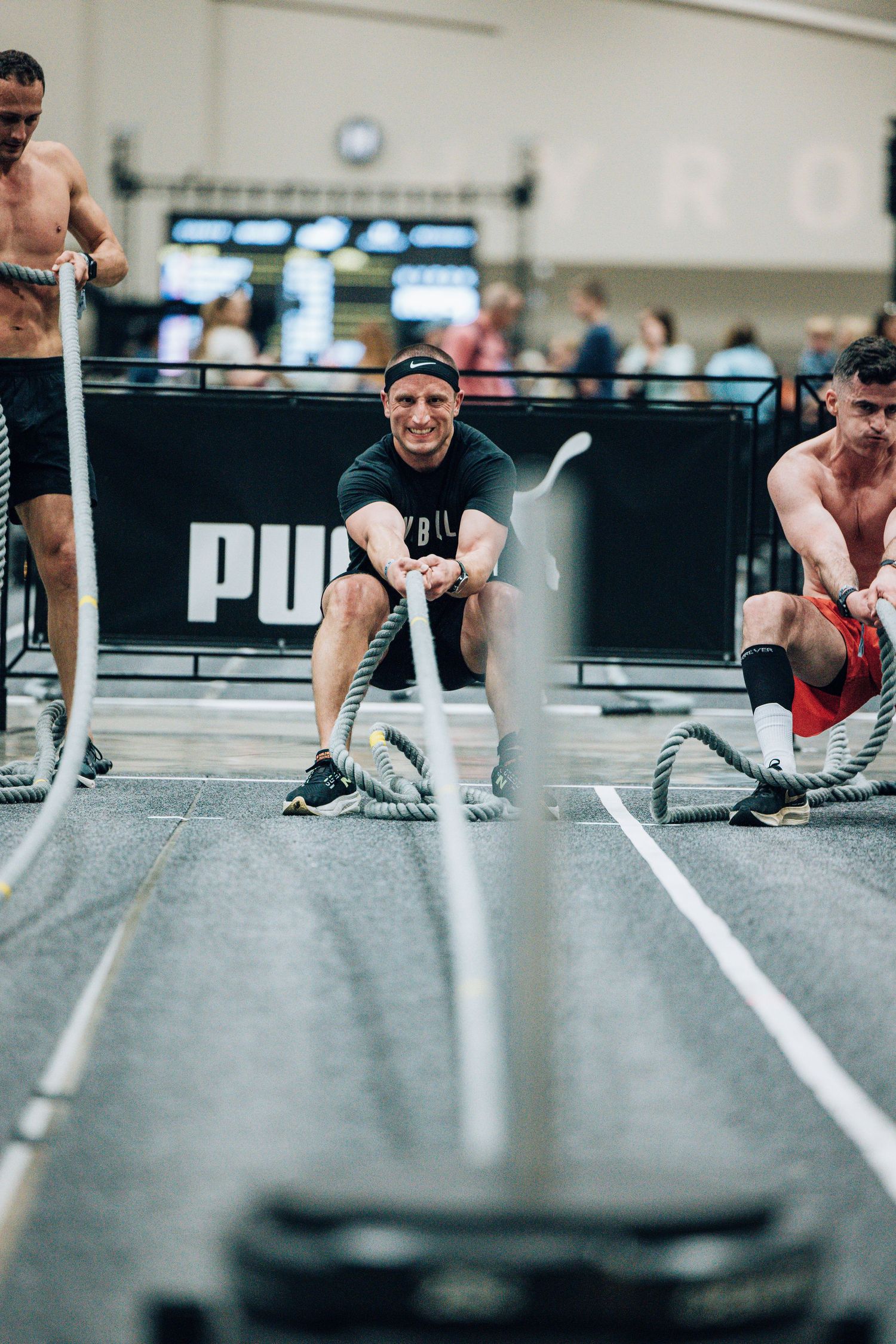 Athletes using battle ropes during a high-intensity gym workout session.