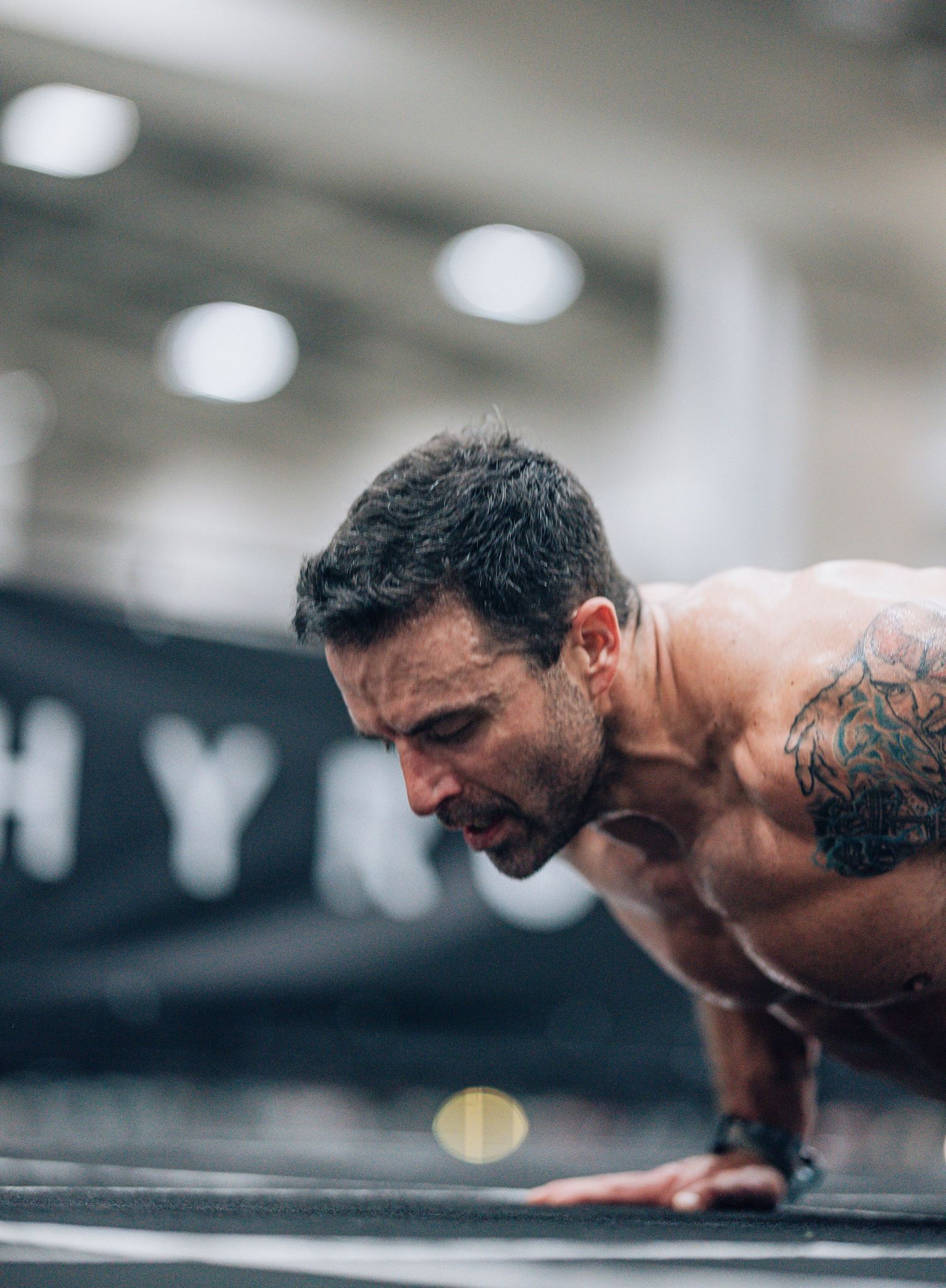 Shirtless athlete performing pushups with intense focus during workout.