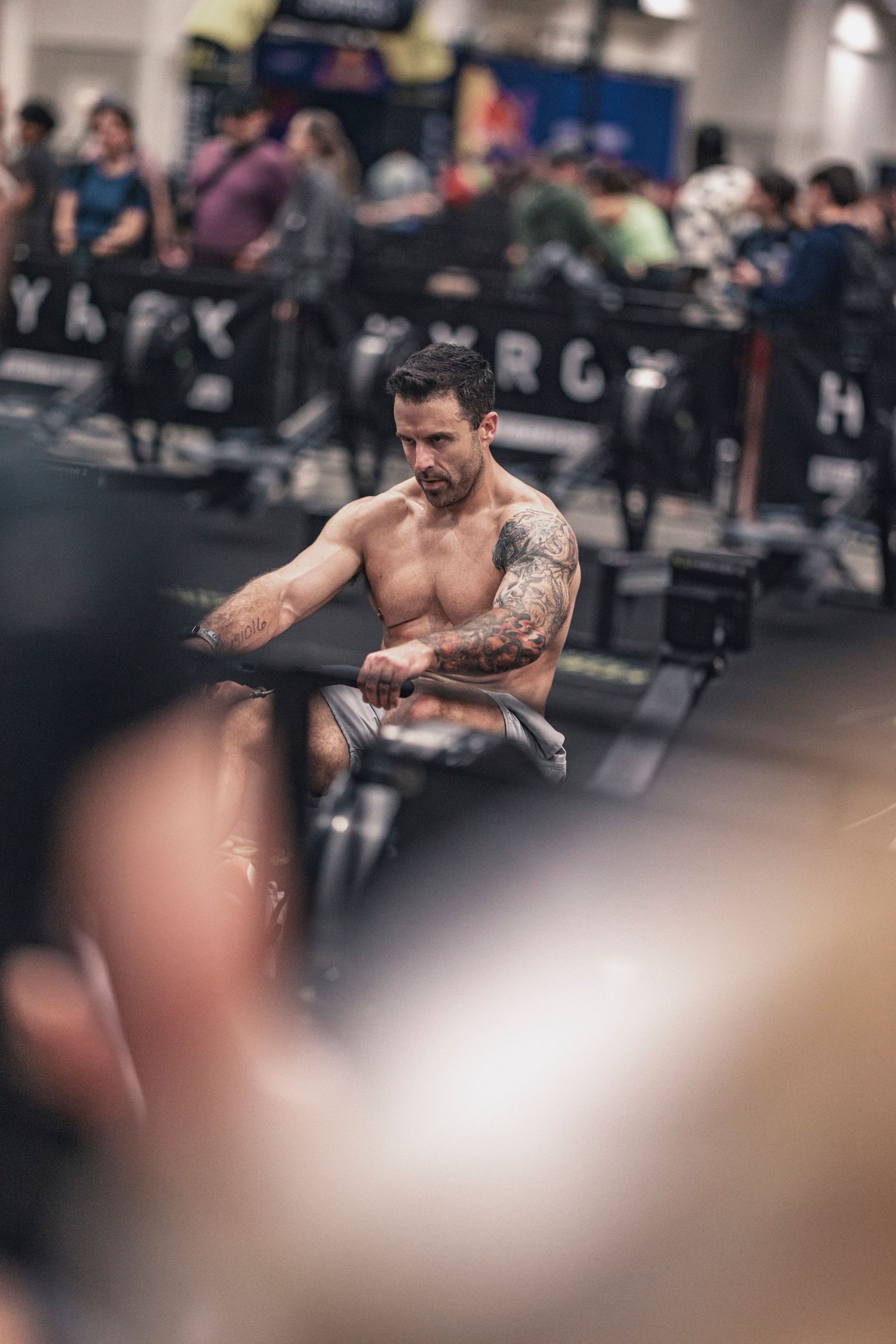 Athlete performing high-intensity rowing workout in a crowded gym environment.