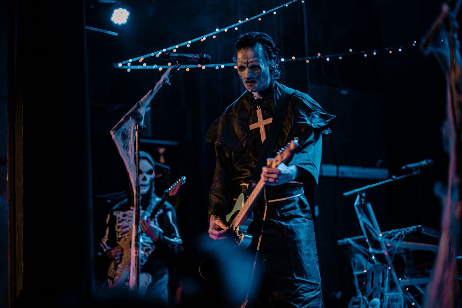 Band members silhouetted against blue stage lights during live performance.
