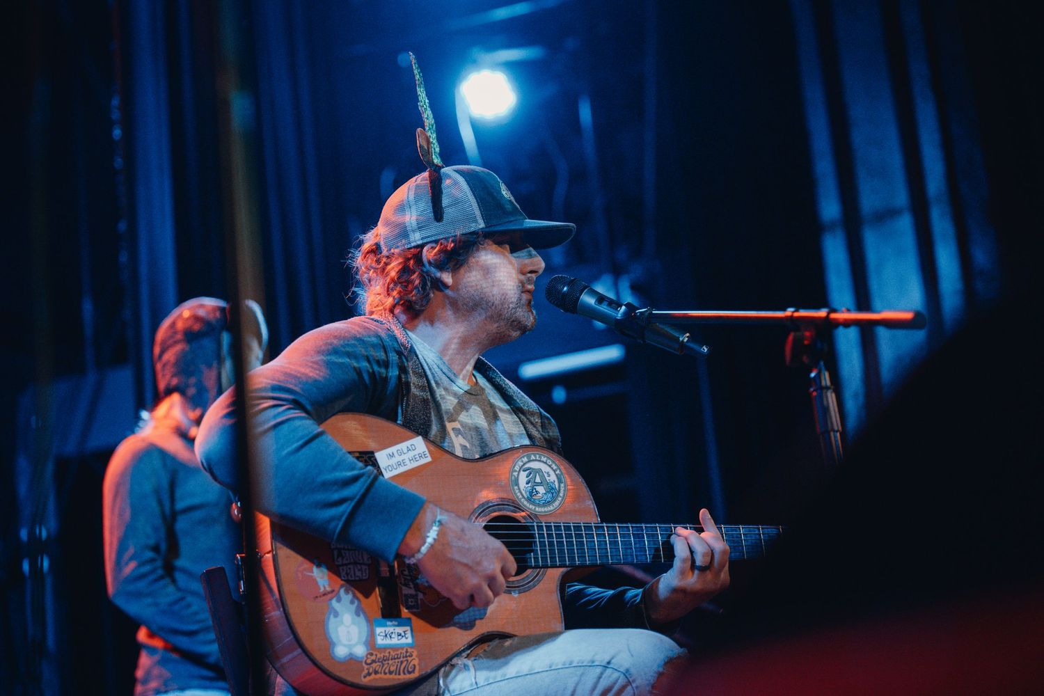 Acoustic guitarist performs under blue spotlight during intimate concert setting.