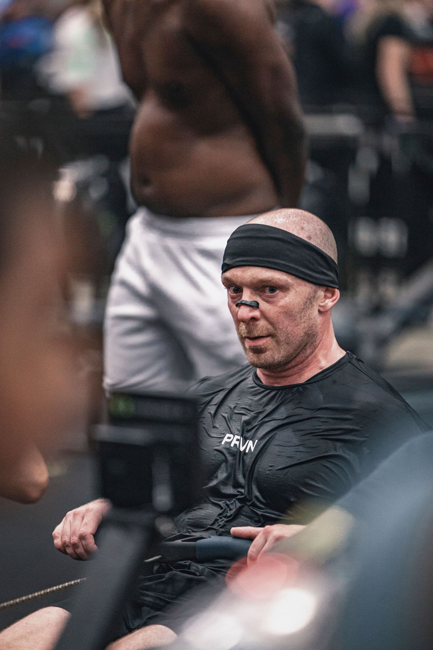 Athletes compete in an indoor fitness competition with sled pushing equipment.
