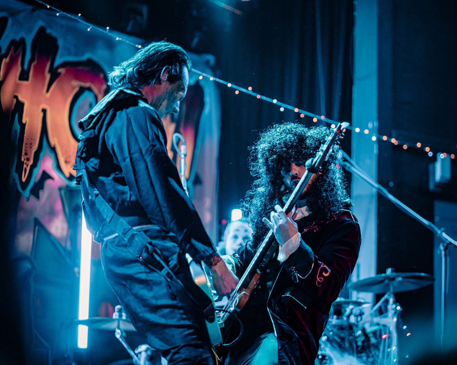 Guitarist performs energetically on stage under dramatic blue lighting at a live concert.