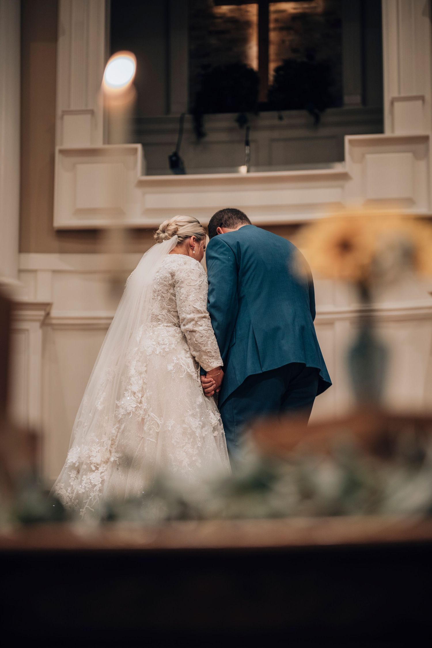 A touching wedding ceremony moment in a church with soft lighting and floral decor.