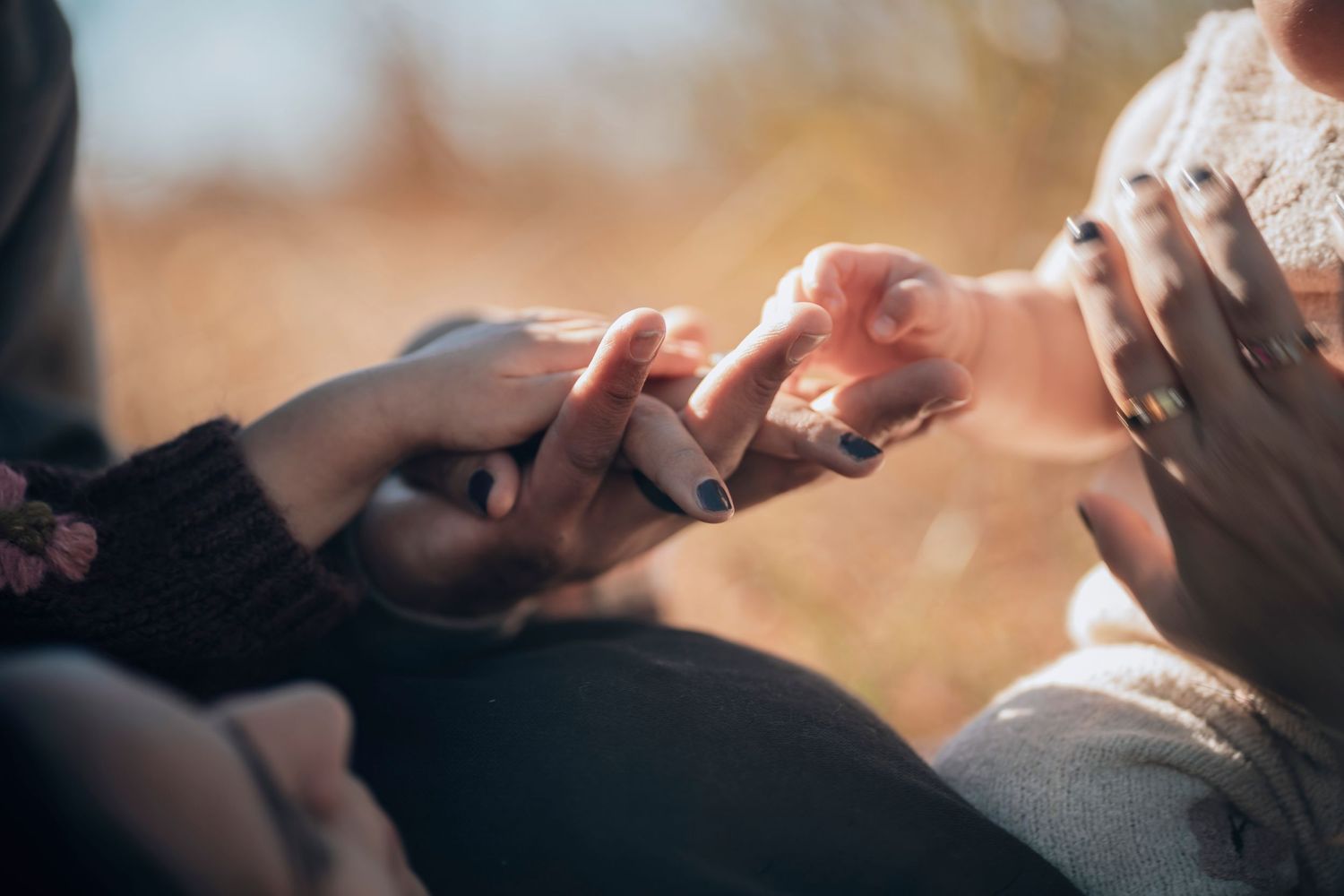 Close up shot of hands reaching towards each other against a warm blurred background.