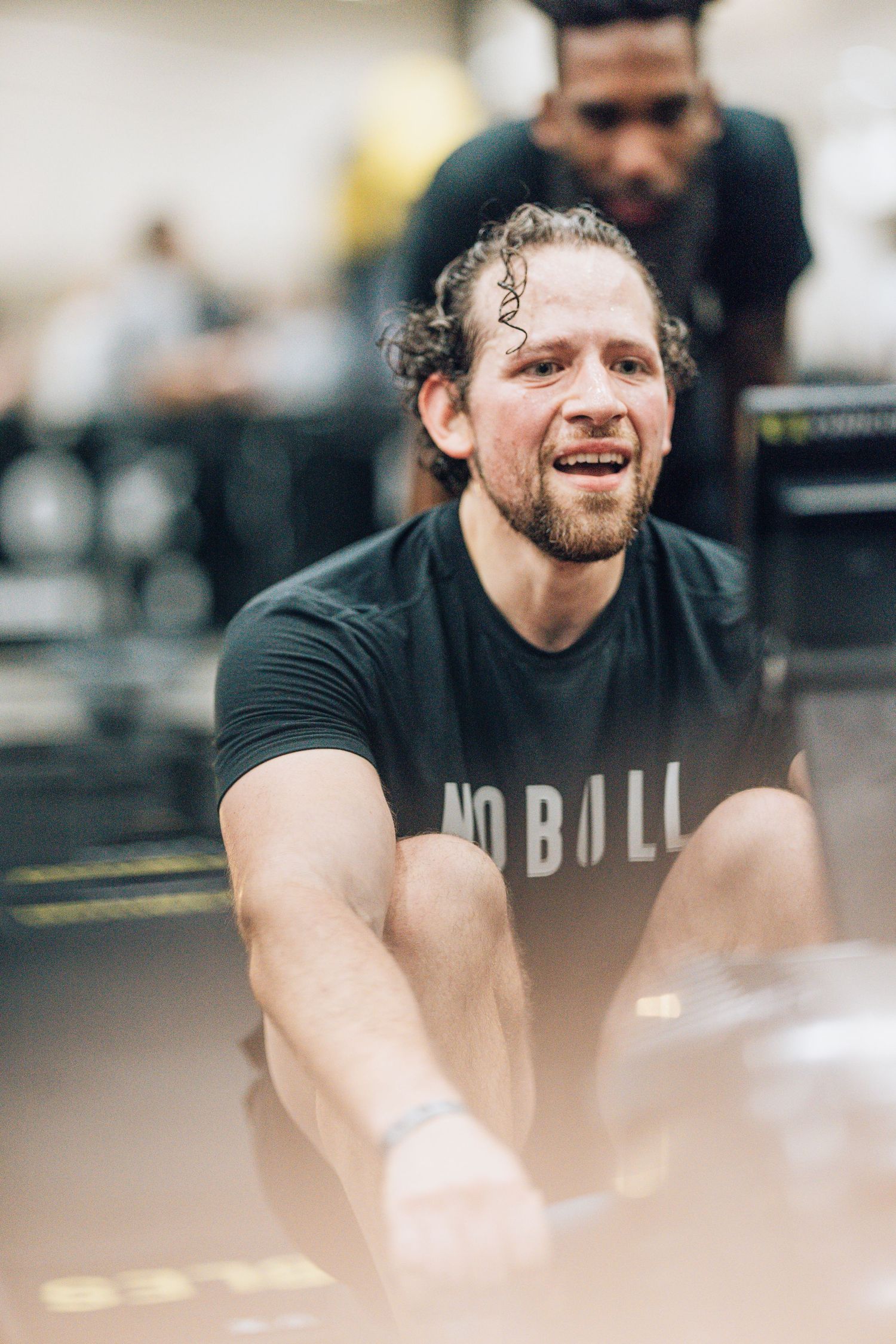 Athletes wearing black workout gear training intensely in a bright gym setting.