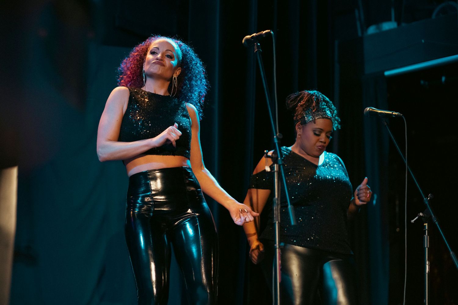 A singer performing on stage under dramatic blue and red lighting.