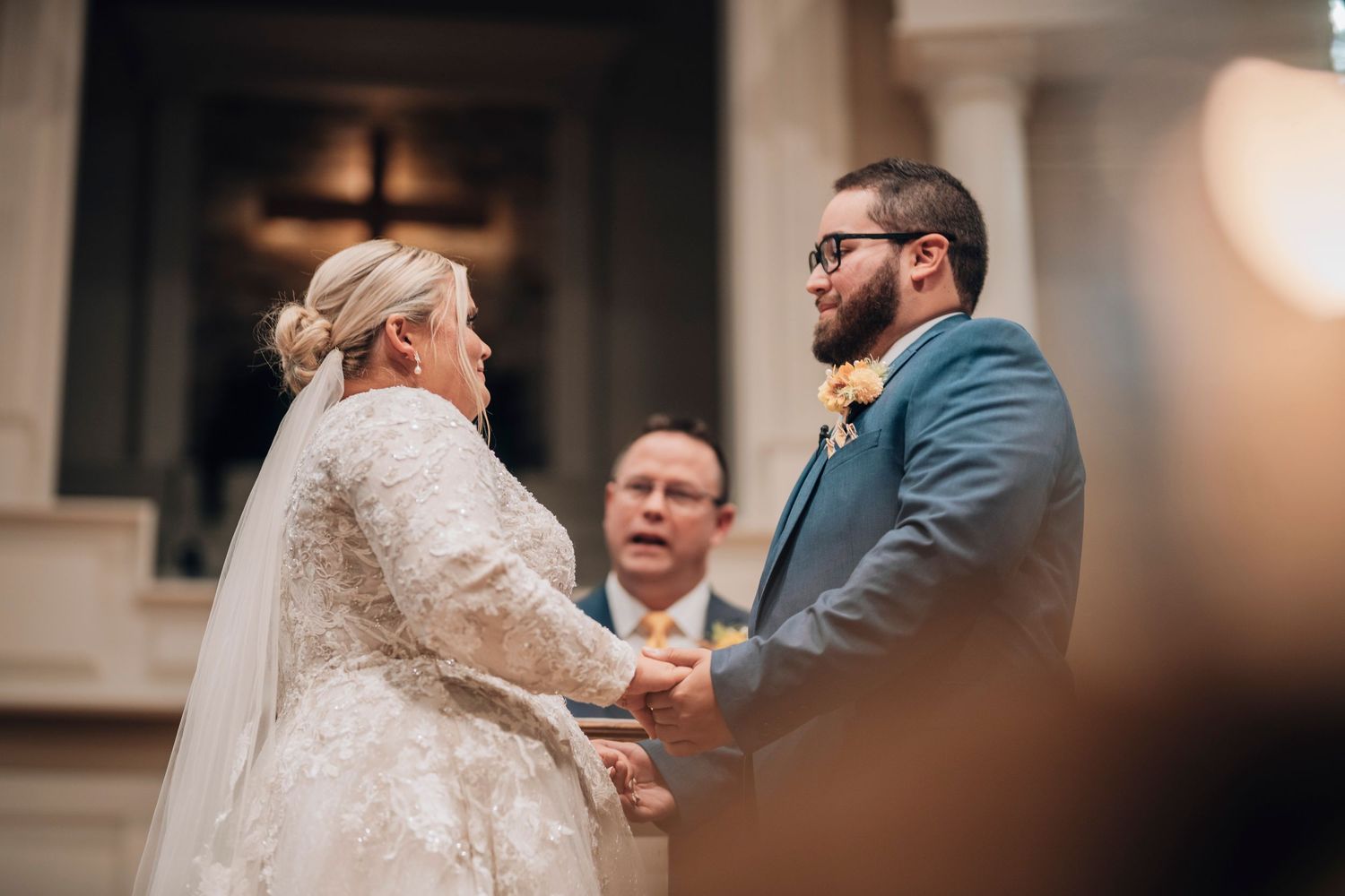 A tender moment during a wedding ceremony in an elegant indoor venue.