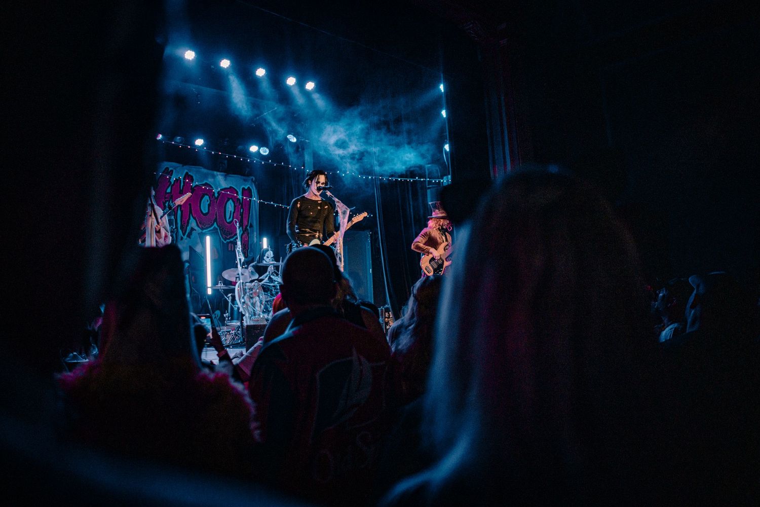 Concert venue with blue stage lighting and silhouetted crowd.