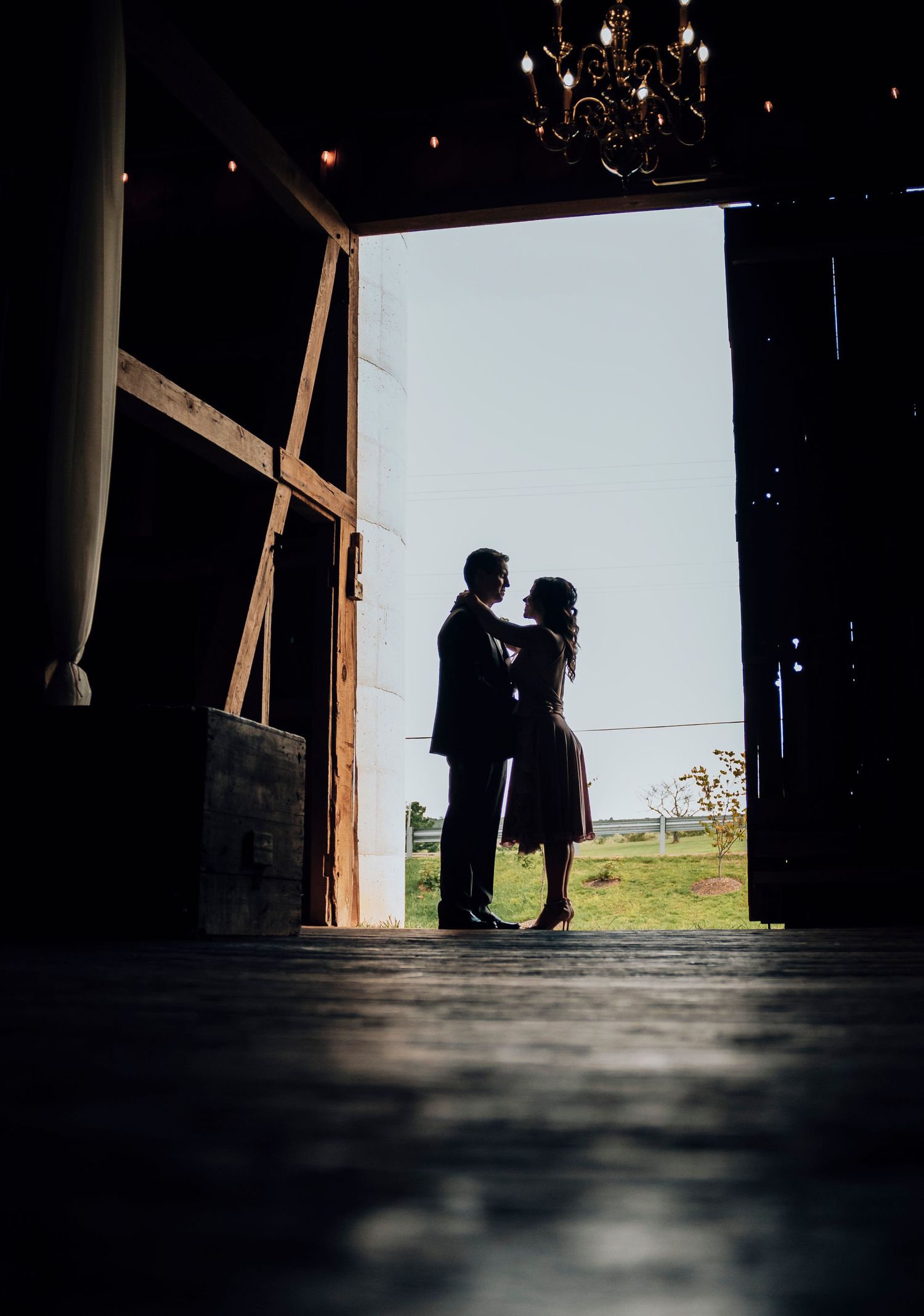 Silhouette of a romantic couple standing in a doorway against bright backlighting.