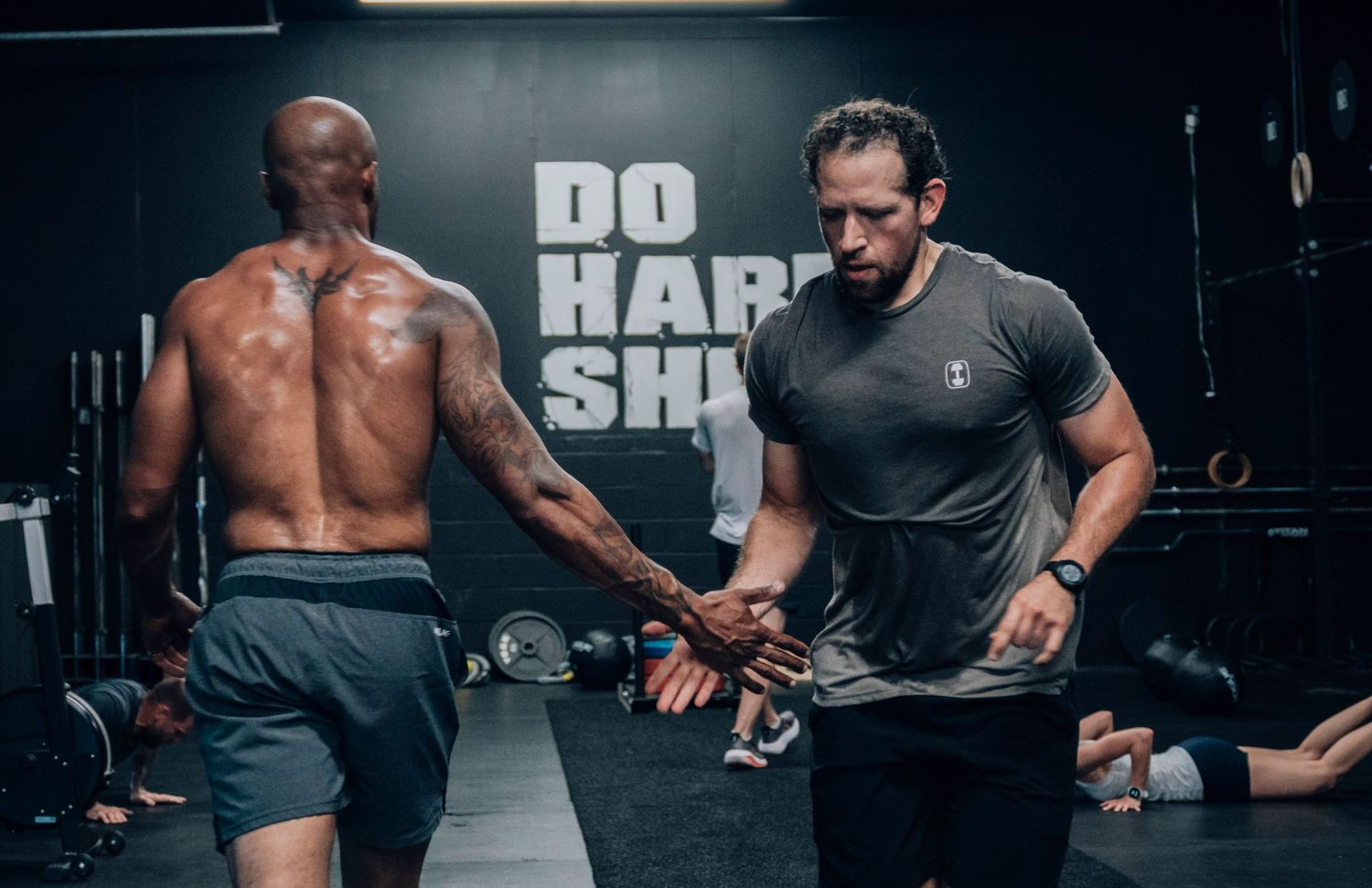 Athletes working out intensely in a dark gym environment with fitness equipment.