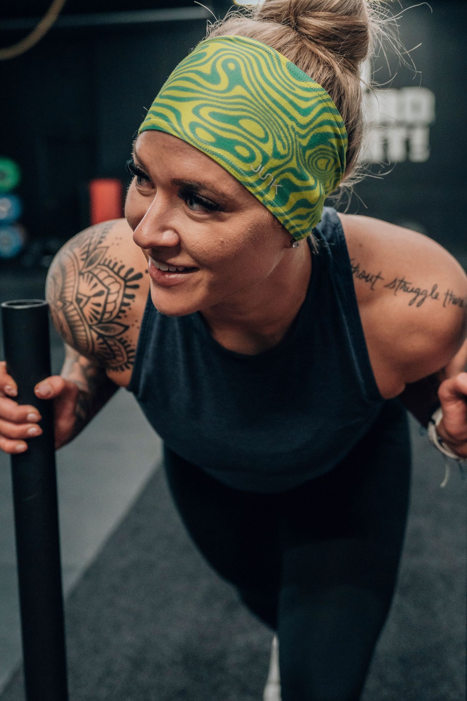 Athlete wearing green patterned headband and black tank top during workout.