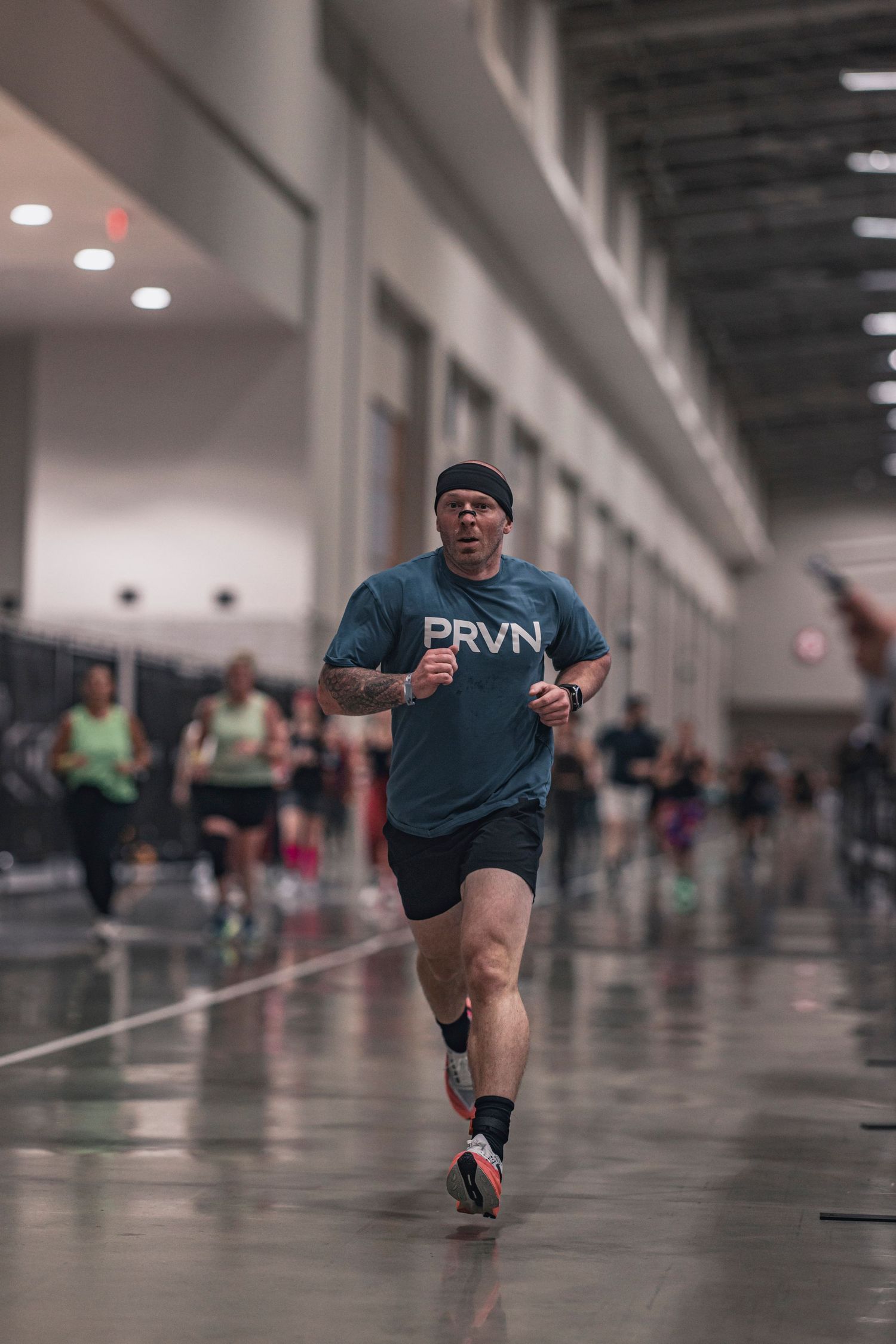 Runner in PRVN shirt jogging through an indoor training facility.
