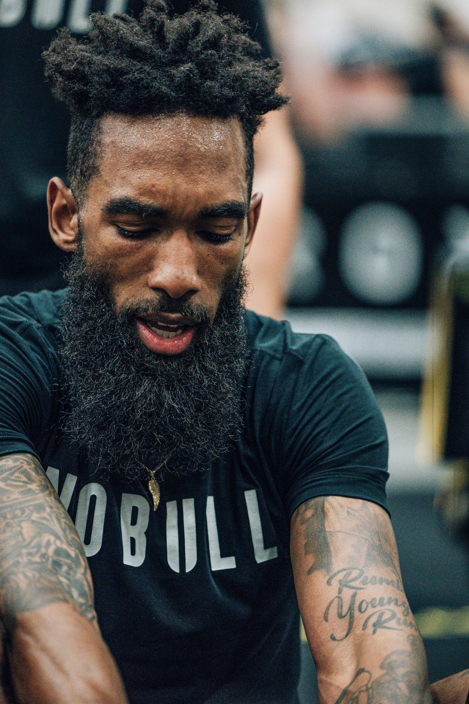 Close-up of a tattooed athlete wearing a black No Bull shirt during a workout.