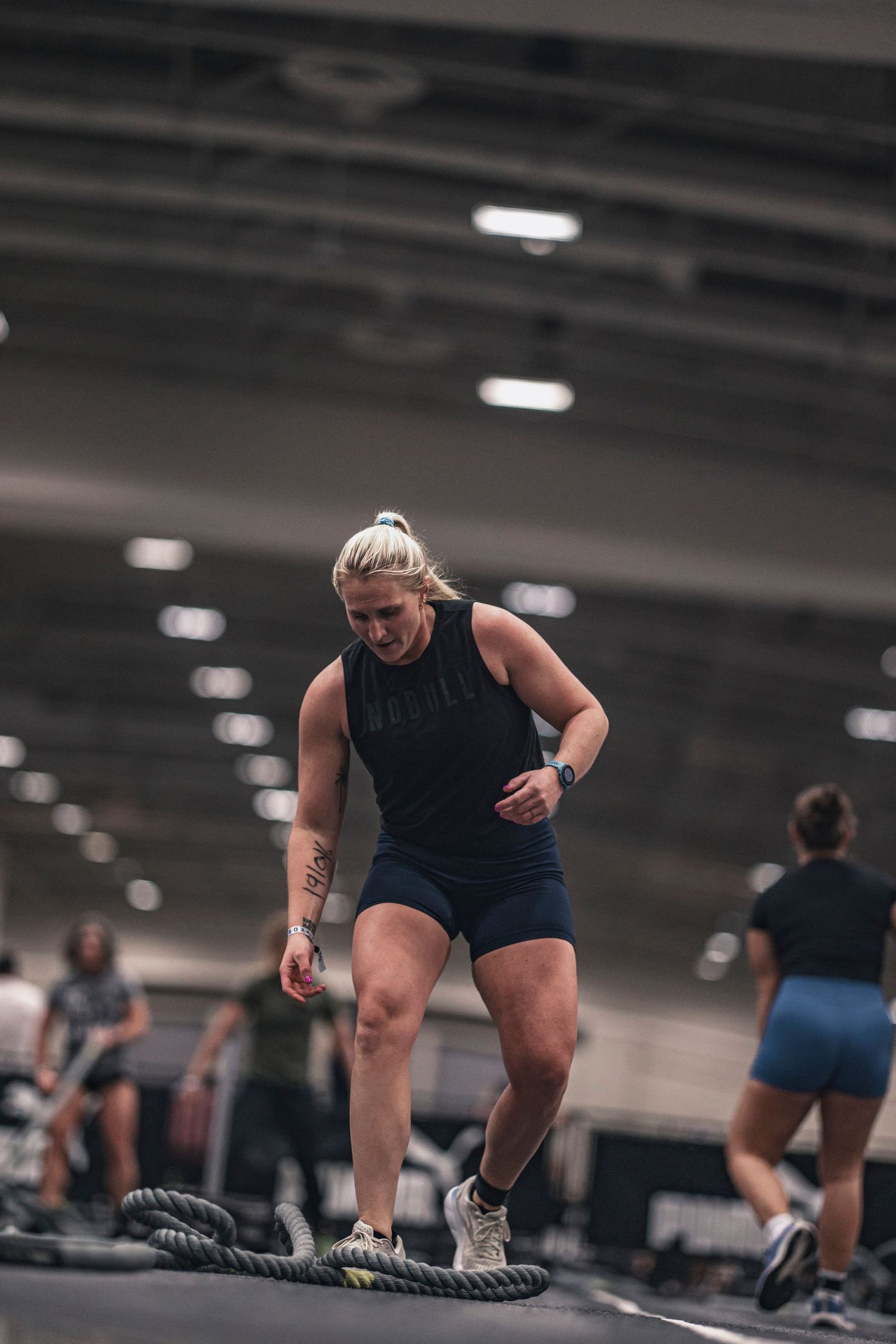 Athletes performing rope exercises during an intense training session in a modern gym facility.