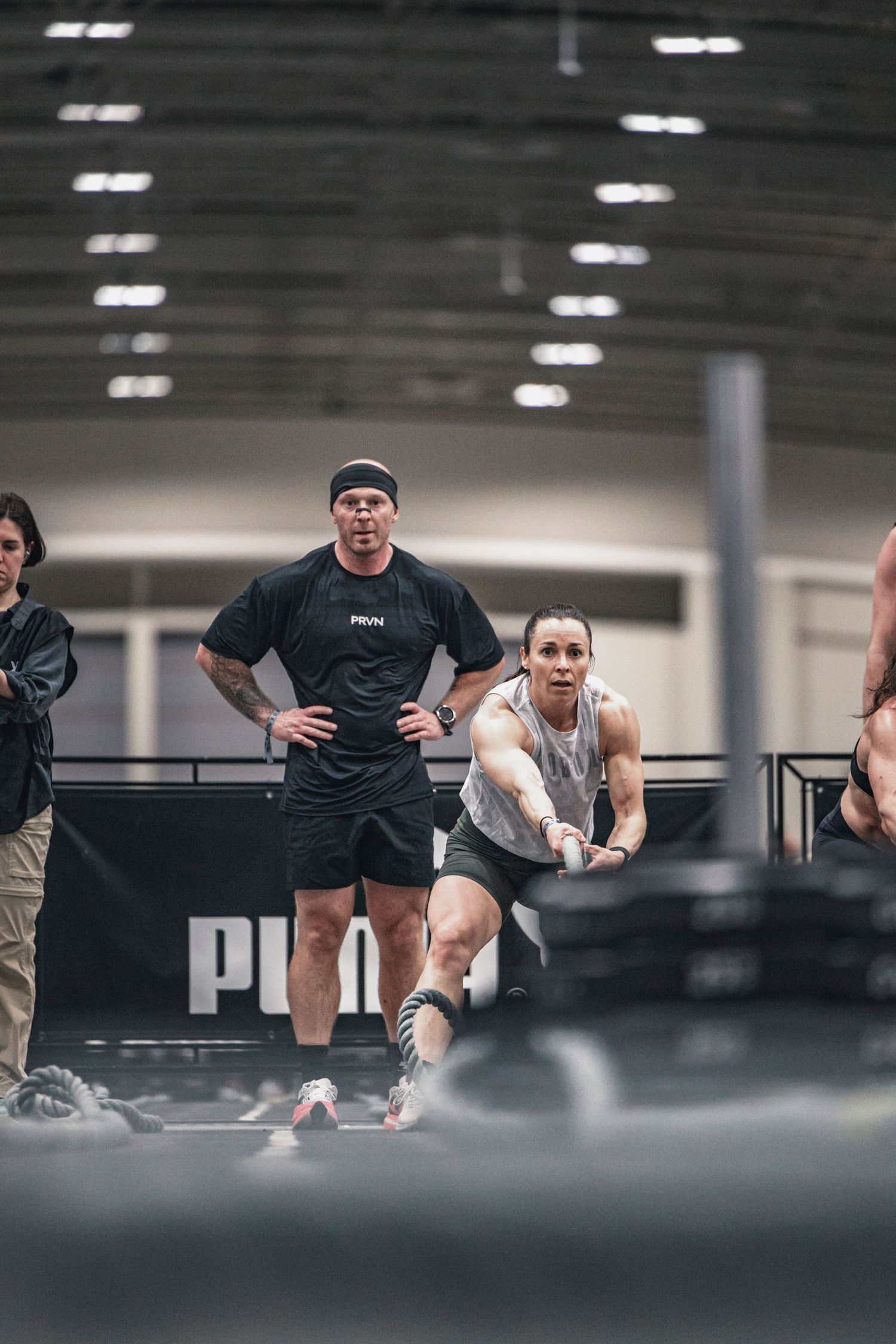 Wide shot of athletes performing synchronized sled push exercises in a large indoor space.