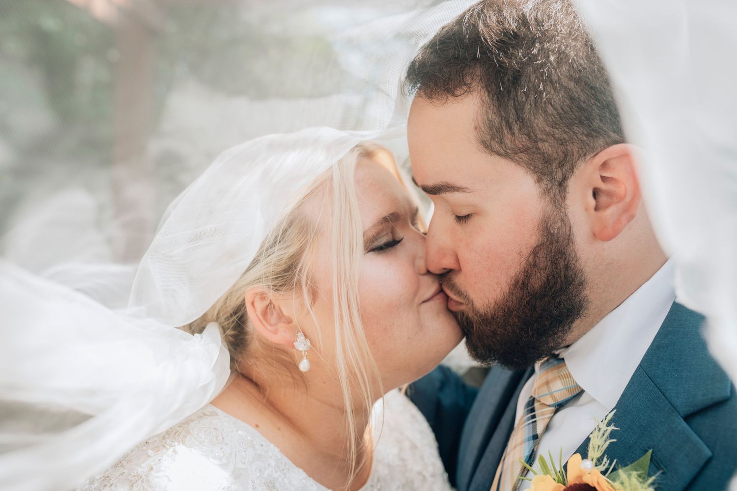An intimate wedding portrait captured through flowing white veil in natural light.