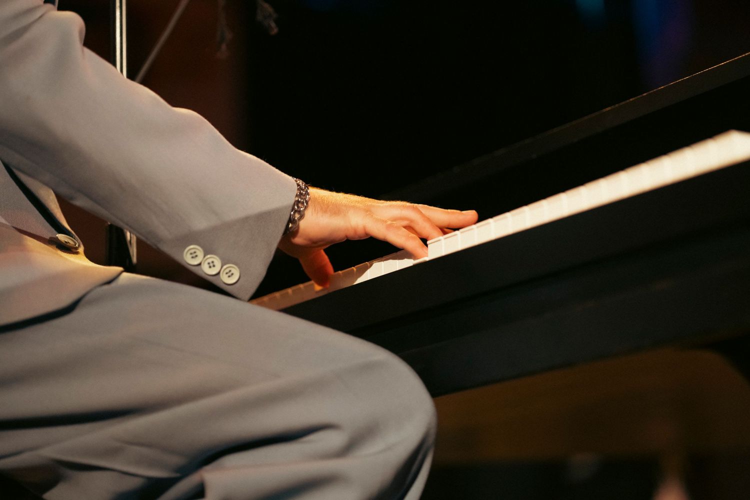 Close-up shot of hands playing piano keys on a black grand piano.