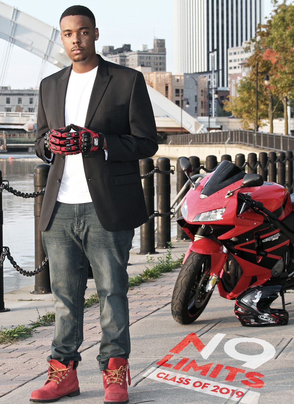 Person in casual attire standing next to a red motorcycle on an urban street.