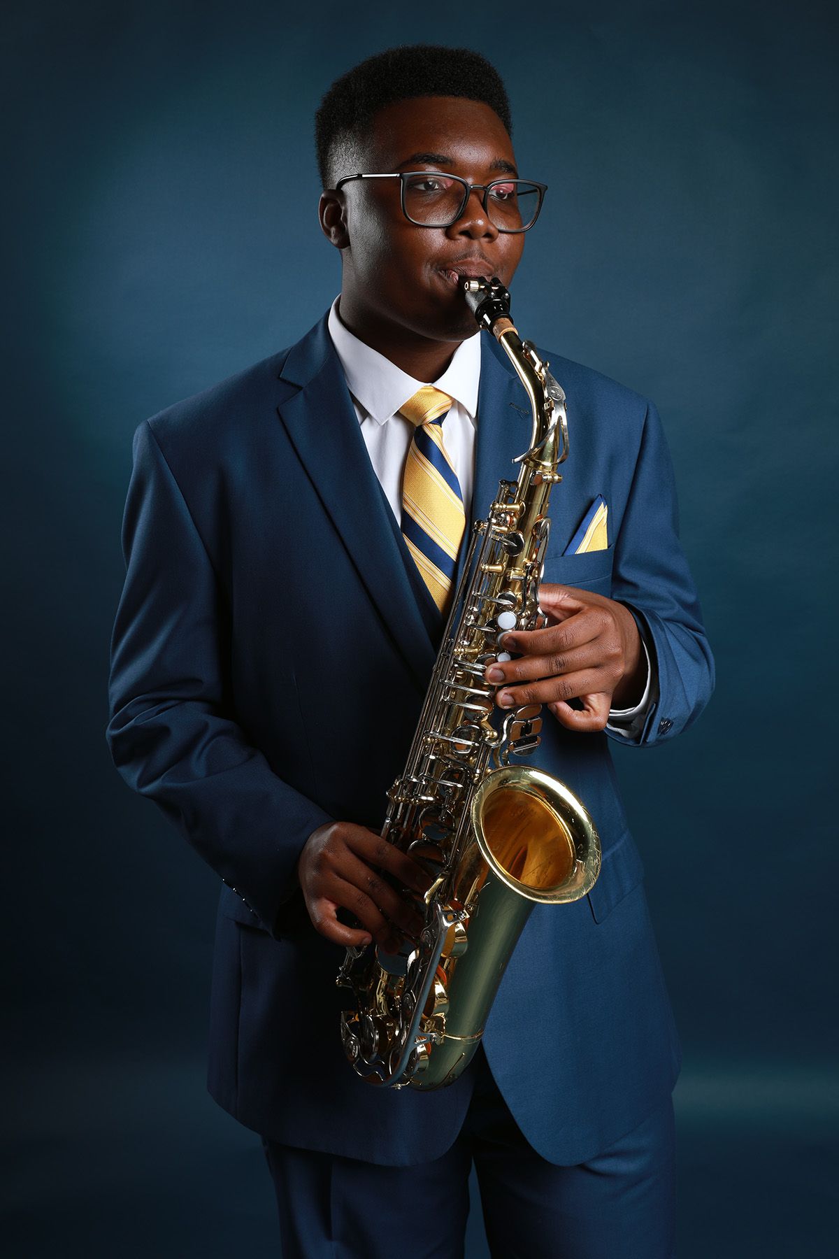Professional sequence showing musician playing saxophone in navy suit with yellow tie.