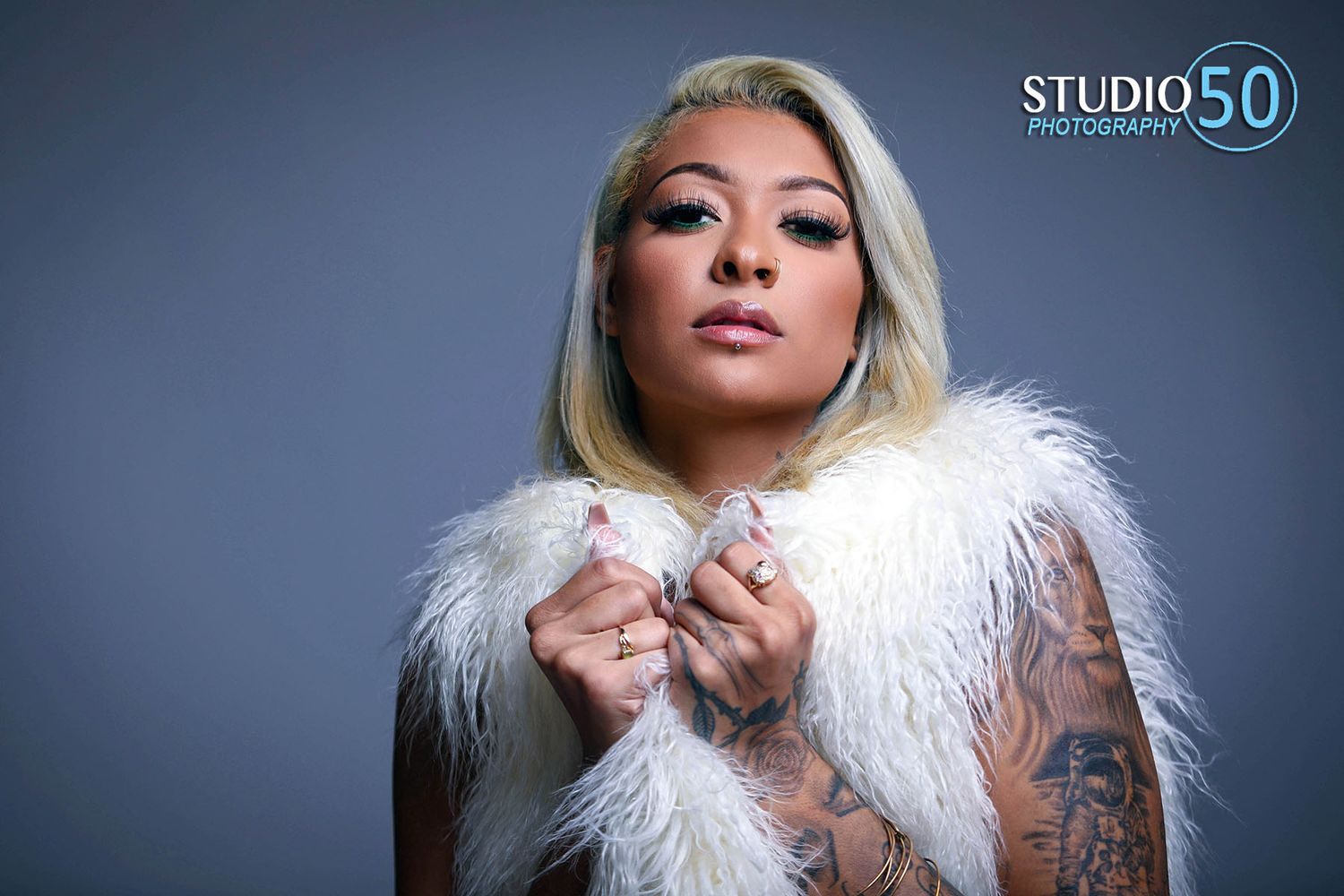 Glamour portraits featuring model in white fur against blue studio background.