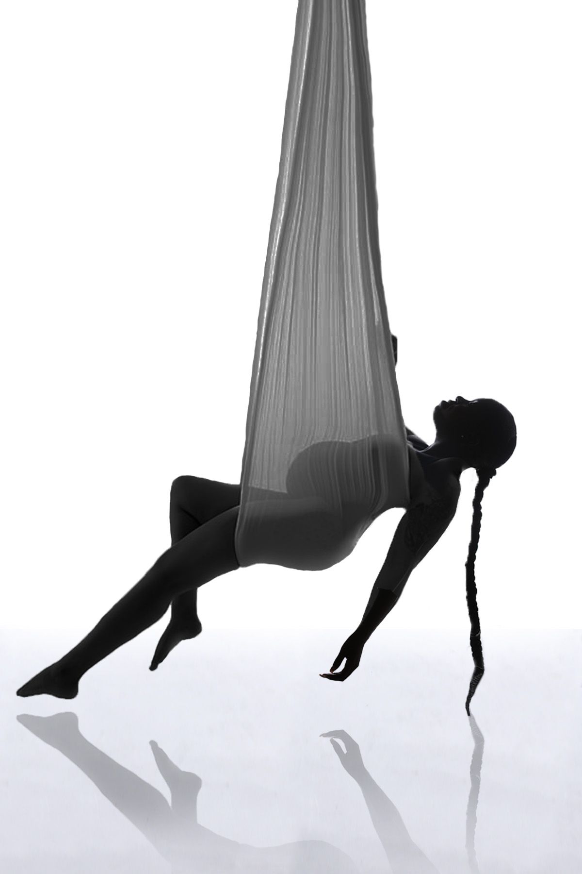 Artistic silhouette of person performing aerial dance in fabric.