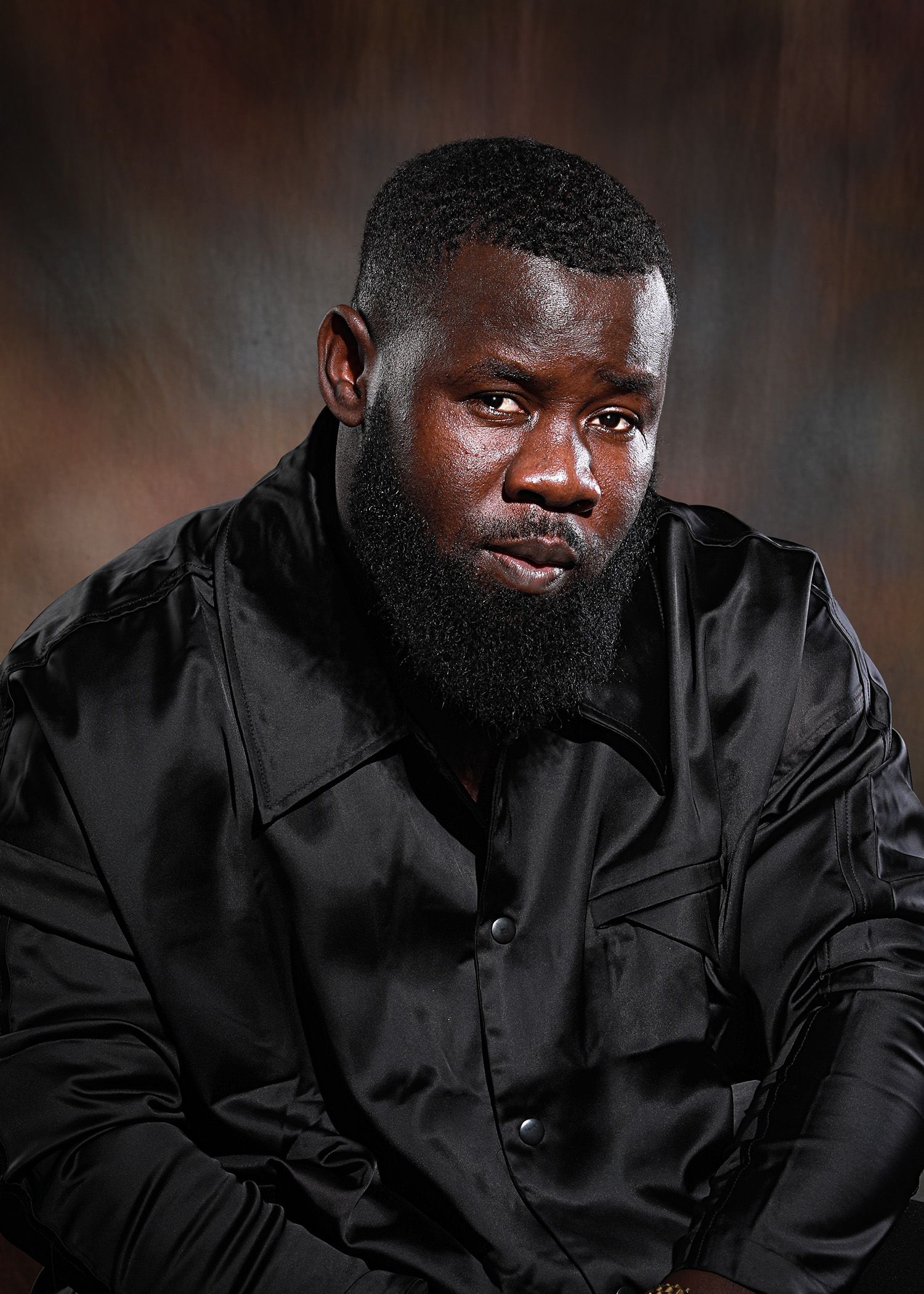 Fashion portrait in black clothing against dramatic dark background.