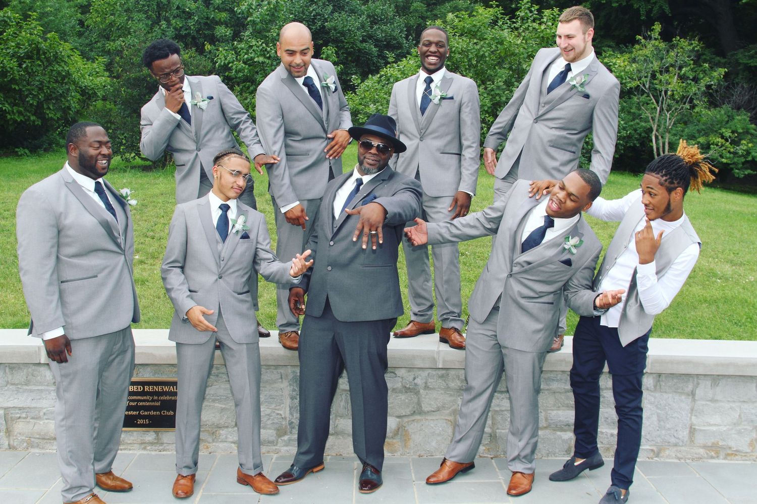 Wedding party in grey suits posing together on outdoor stone steps.