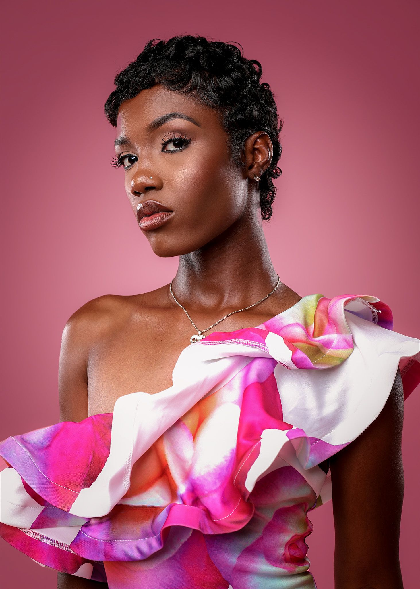 Fashion portrait featuring vibrant pink and white ruffled asymmetrical top against rose-colored backdrop.