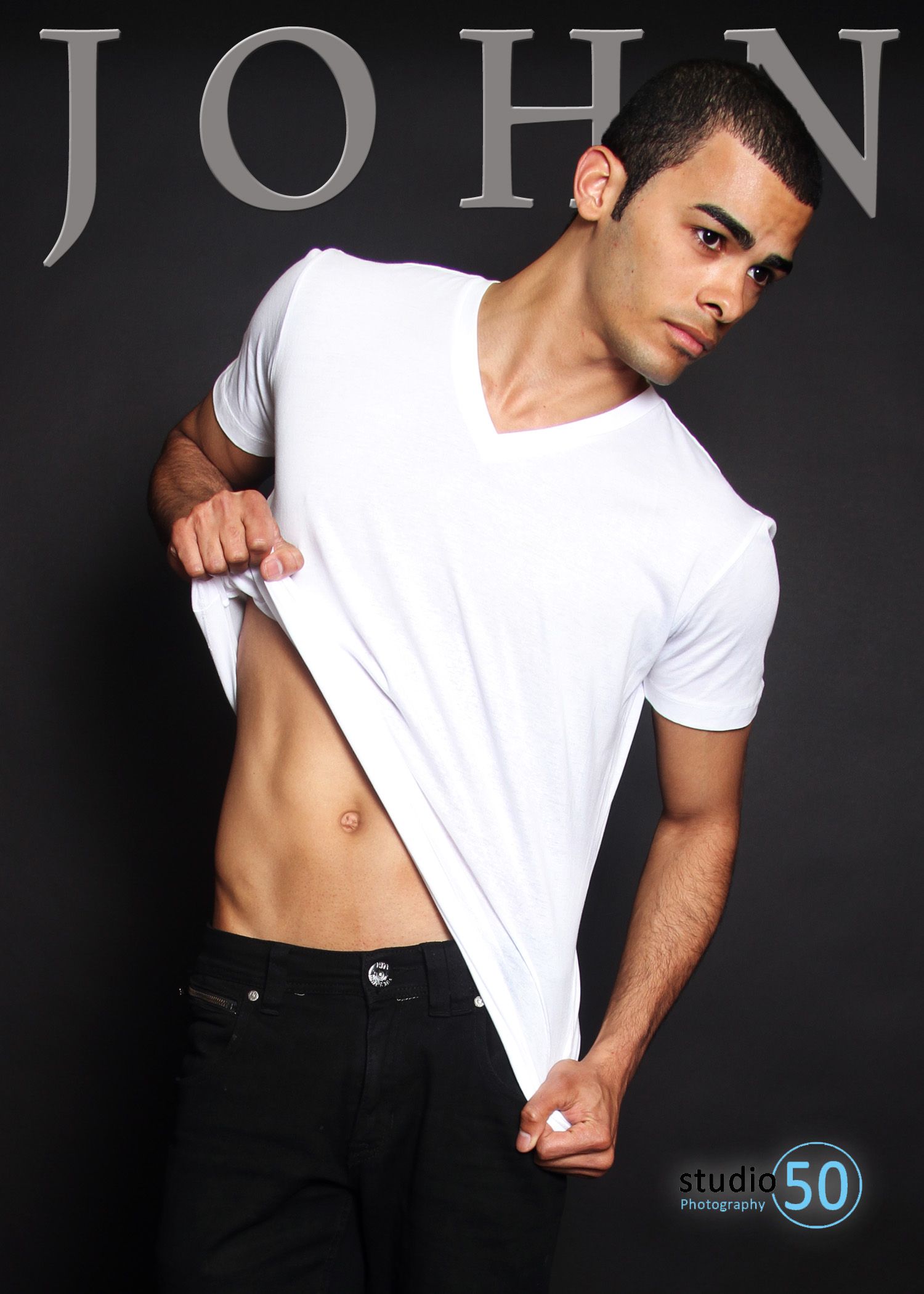 Fashion model in white t-shirt lifting shirt against dark background with text overlay.