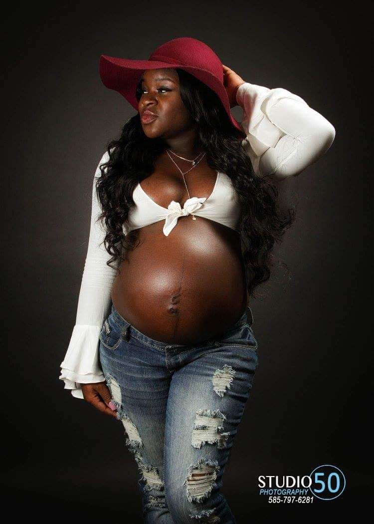 Stylish maternity photo featuring red hat, white top and distressed jeans.