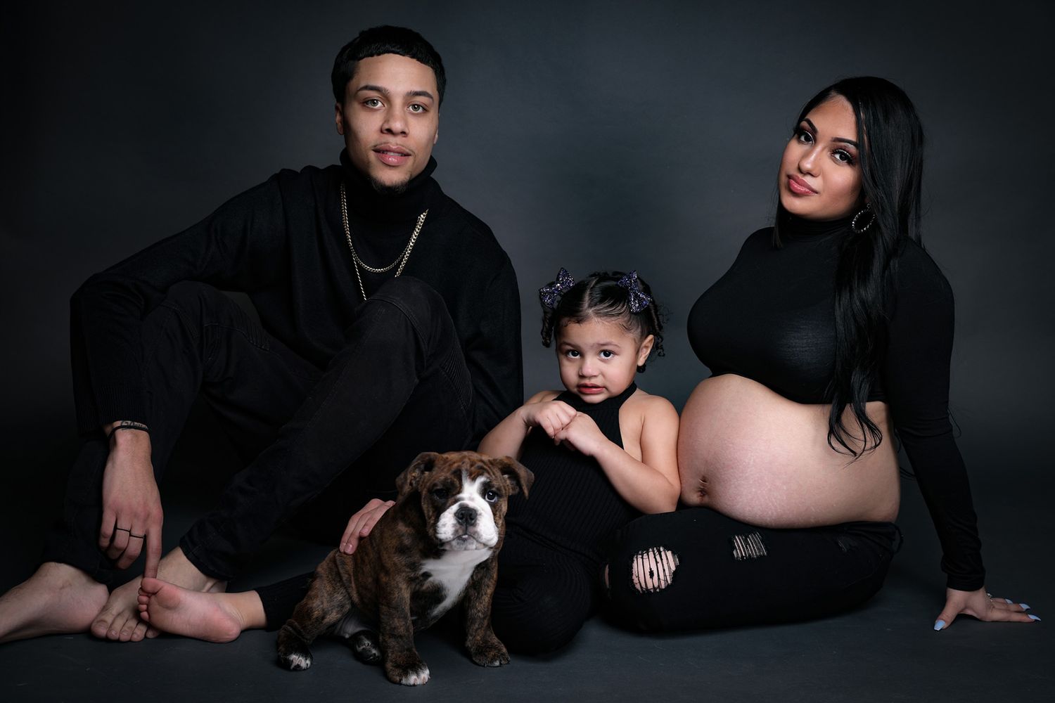 Family maternity photo session with couple lying down and pet dog included.