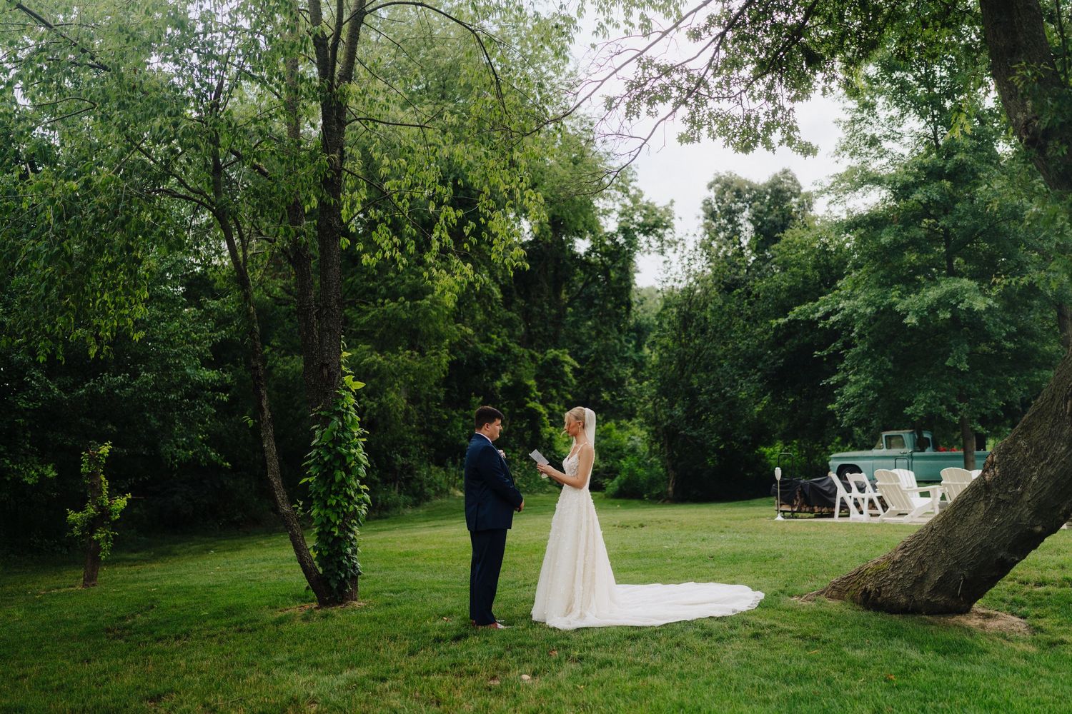 Scenic outdoor wedding venue with mature trees and manicured lawn.