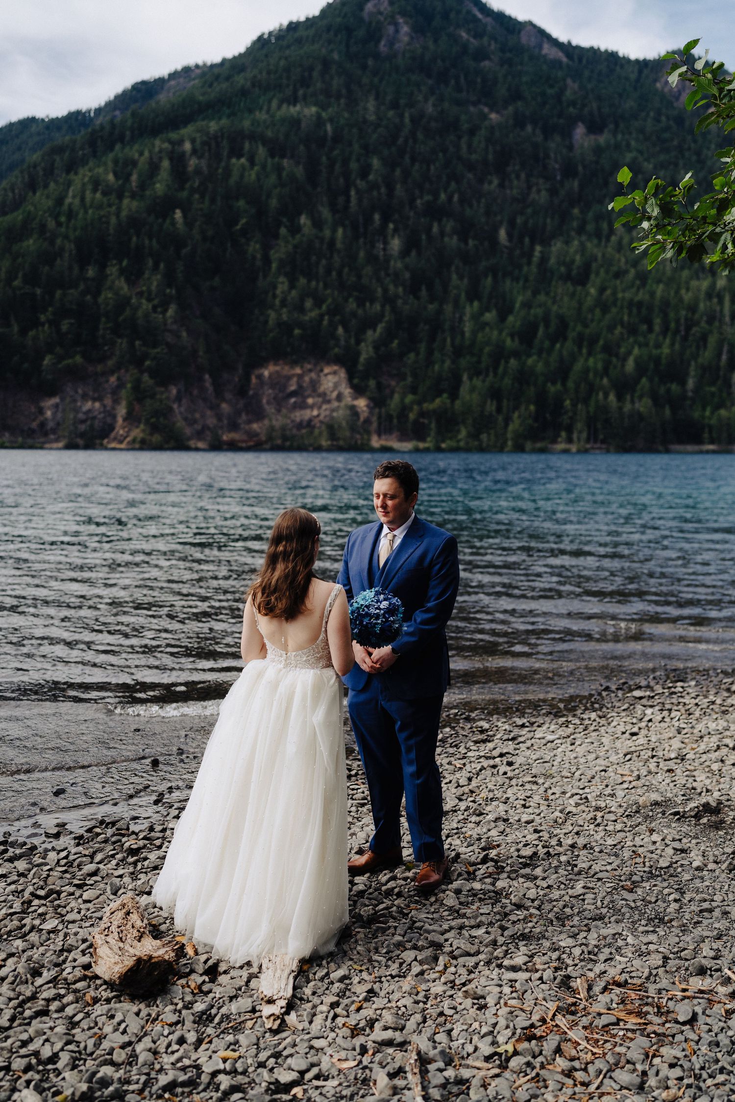A secluded lakeside wedding ceremony with mountains and evergreen forests creating a dramatic backdrop.