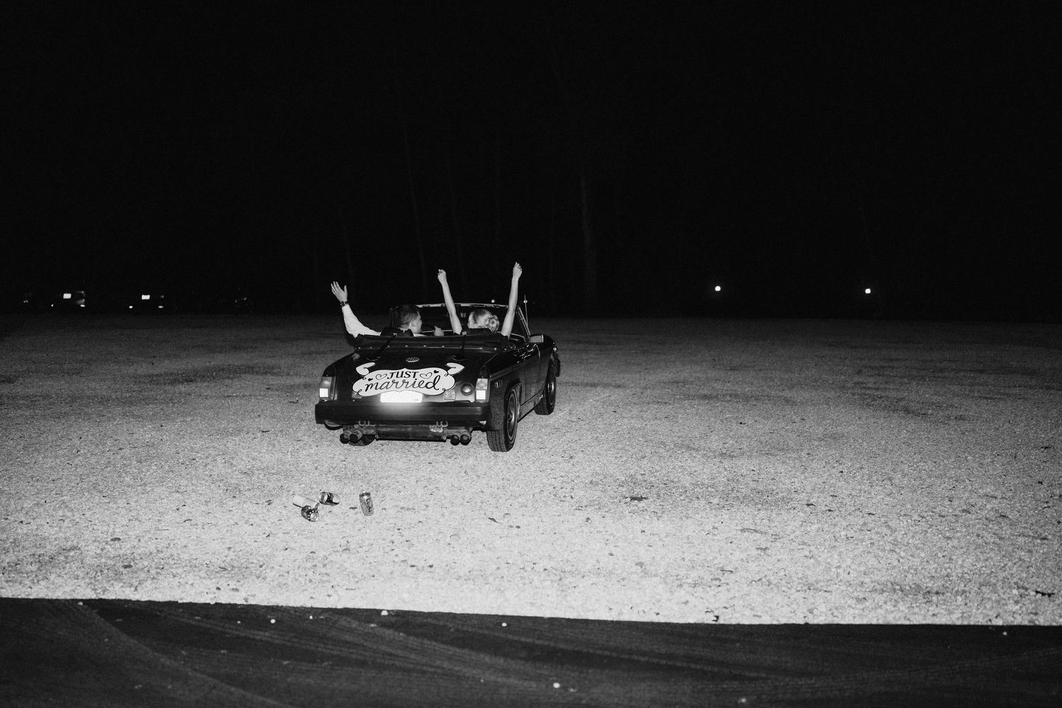 Black and white nighttime silhouettes of people and objects on a beach or sandy surface.