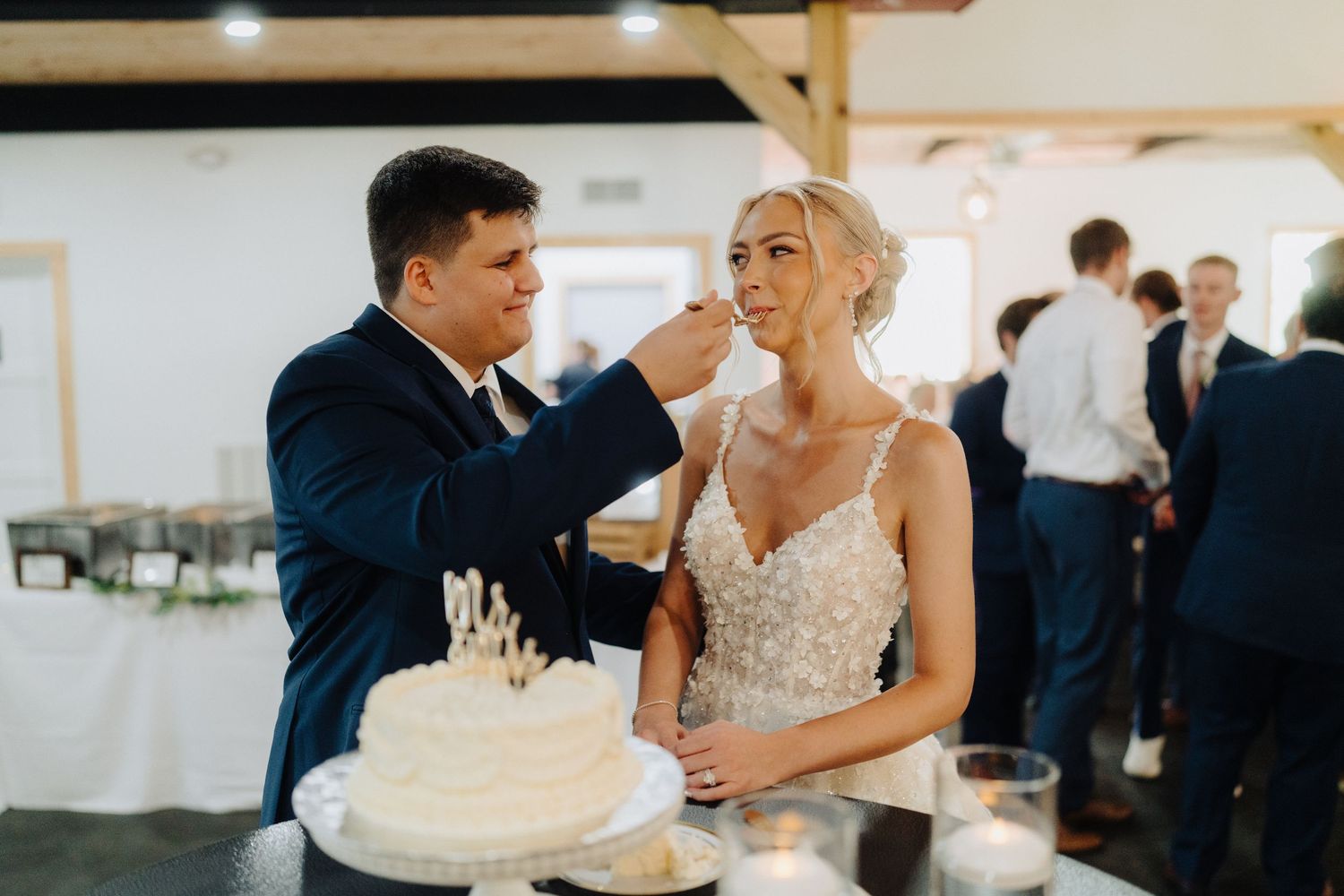Elegant wedding reception setup with white decor and floral arrangements in a bright indoor venue.