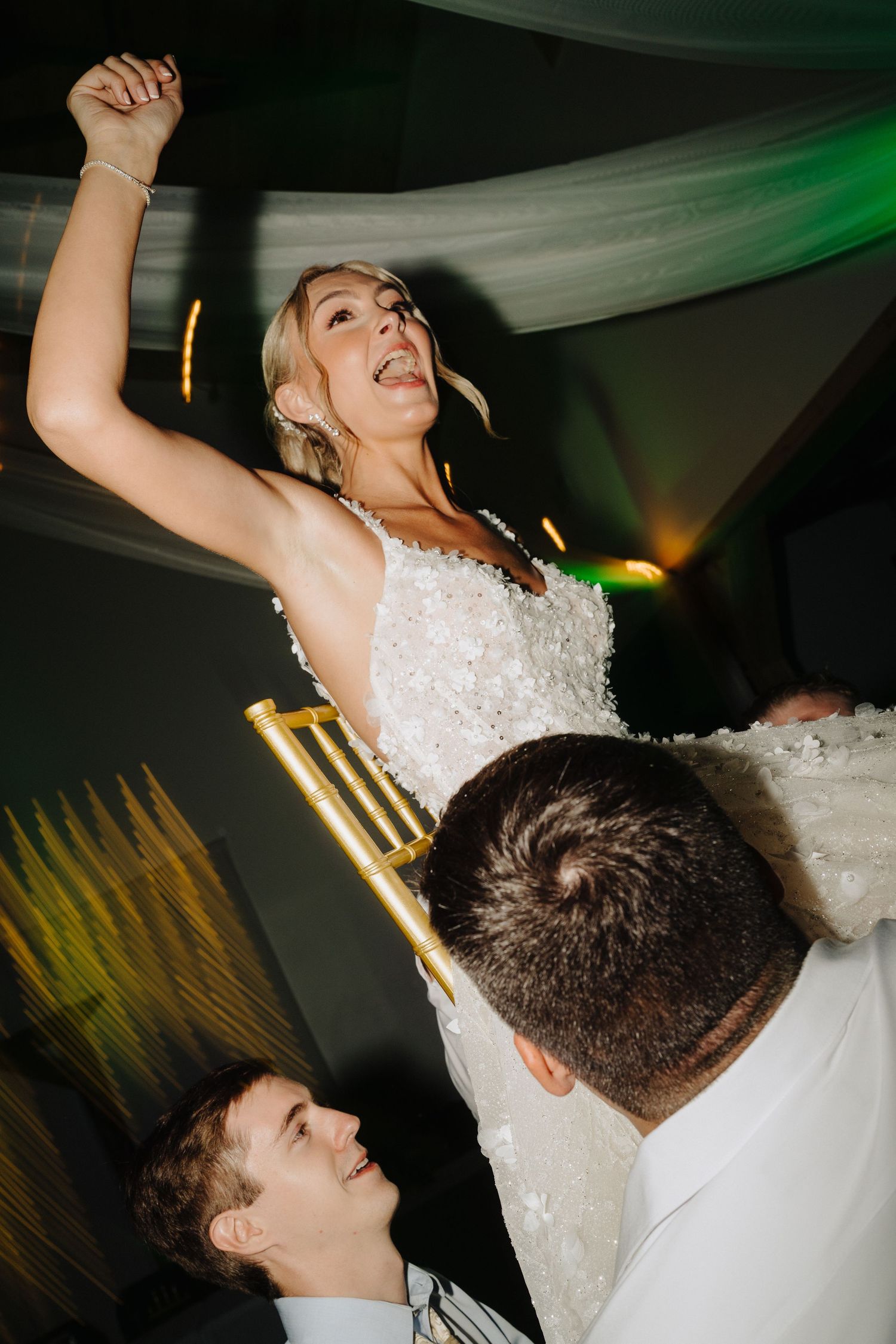 Wedding reception dance party with energetic dancing under mood lighting.